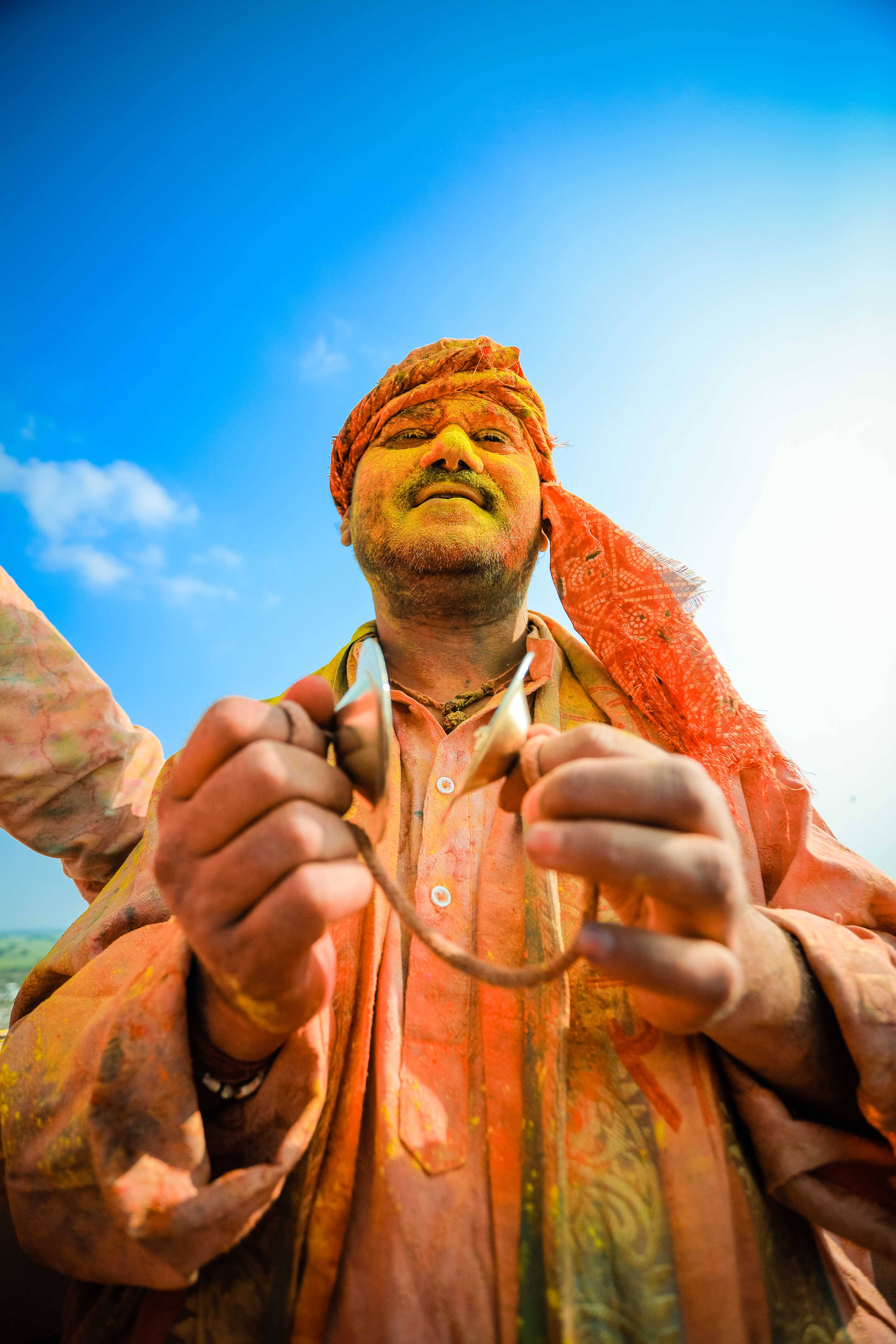 Happy India Holi Celebrator, vibrant orange and yellow powder, stringed instrument, 5K Phone Wallpaper