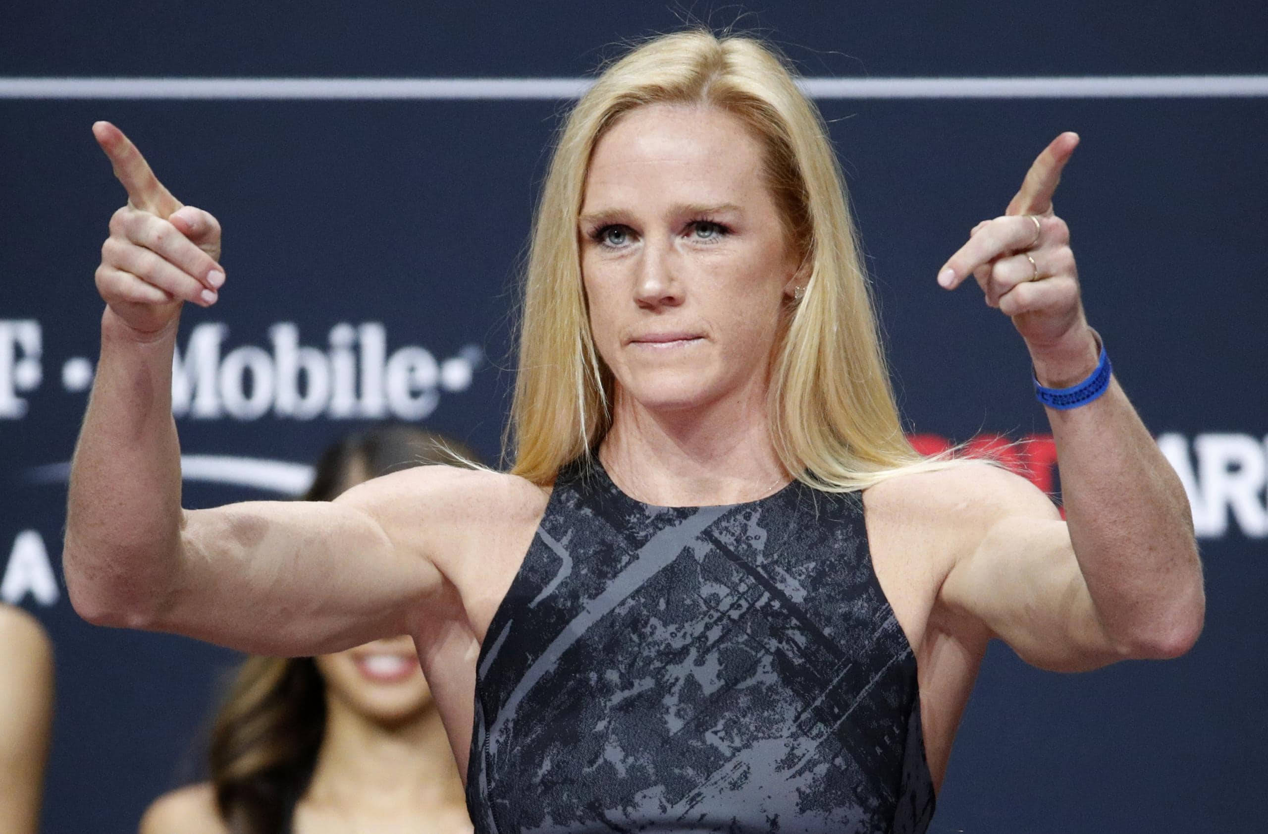 Holly Holm, black patterned top, blue branded backdrop, 2K Desktop Wallpaper