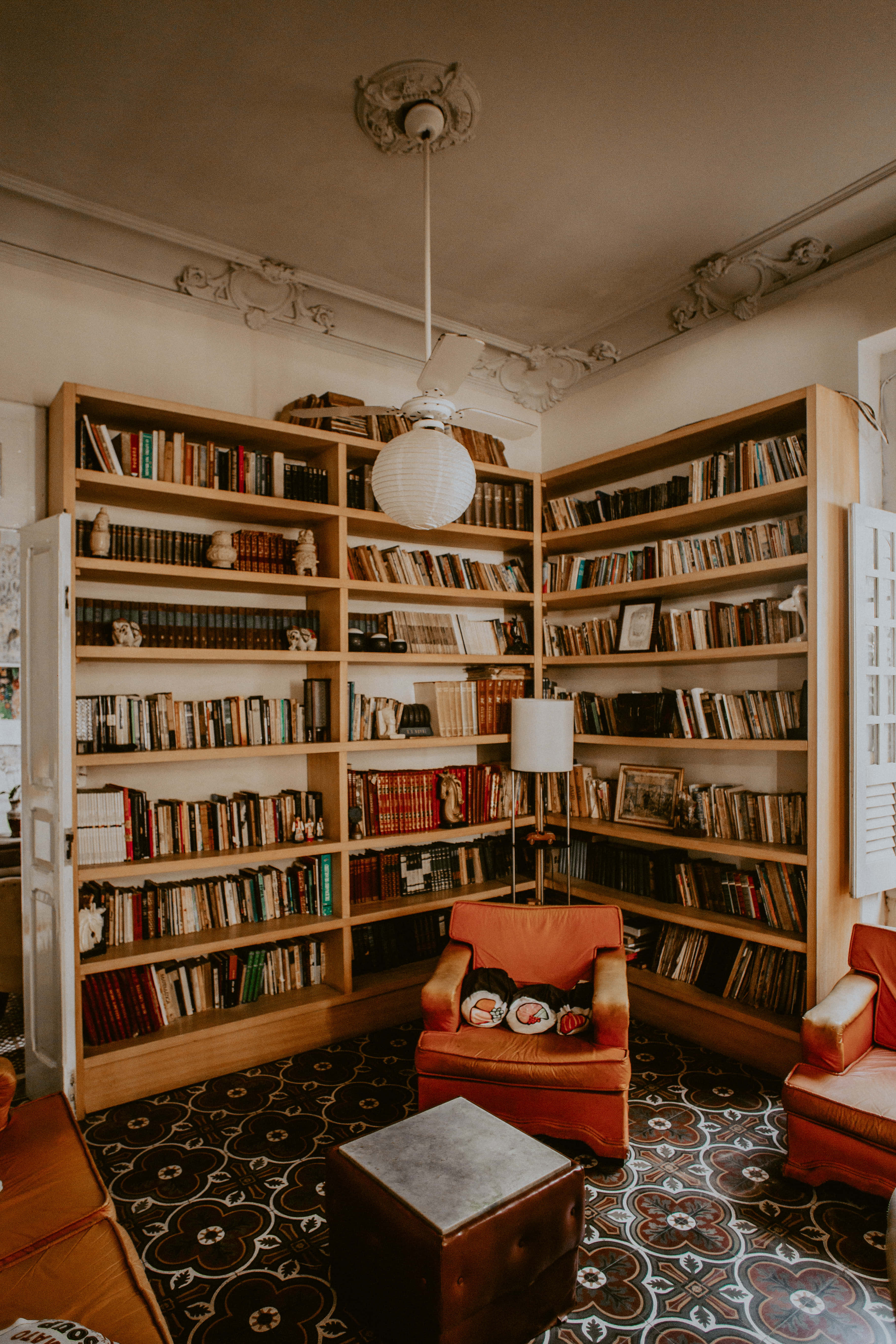 vintage library corner, wooden bookshelves, orange armchairs, 5K Phone Wallpaper