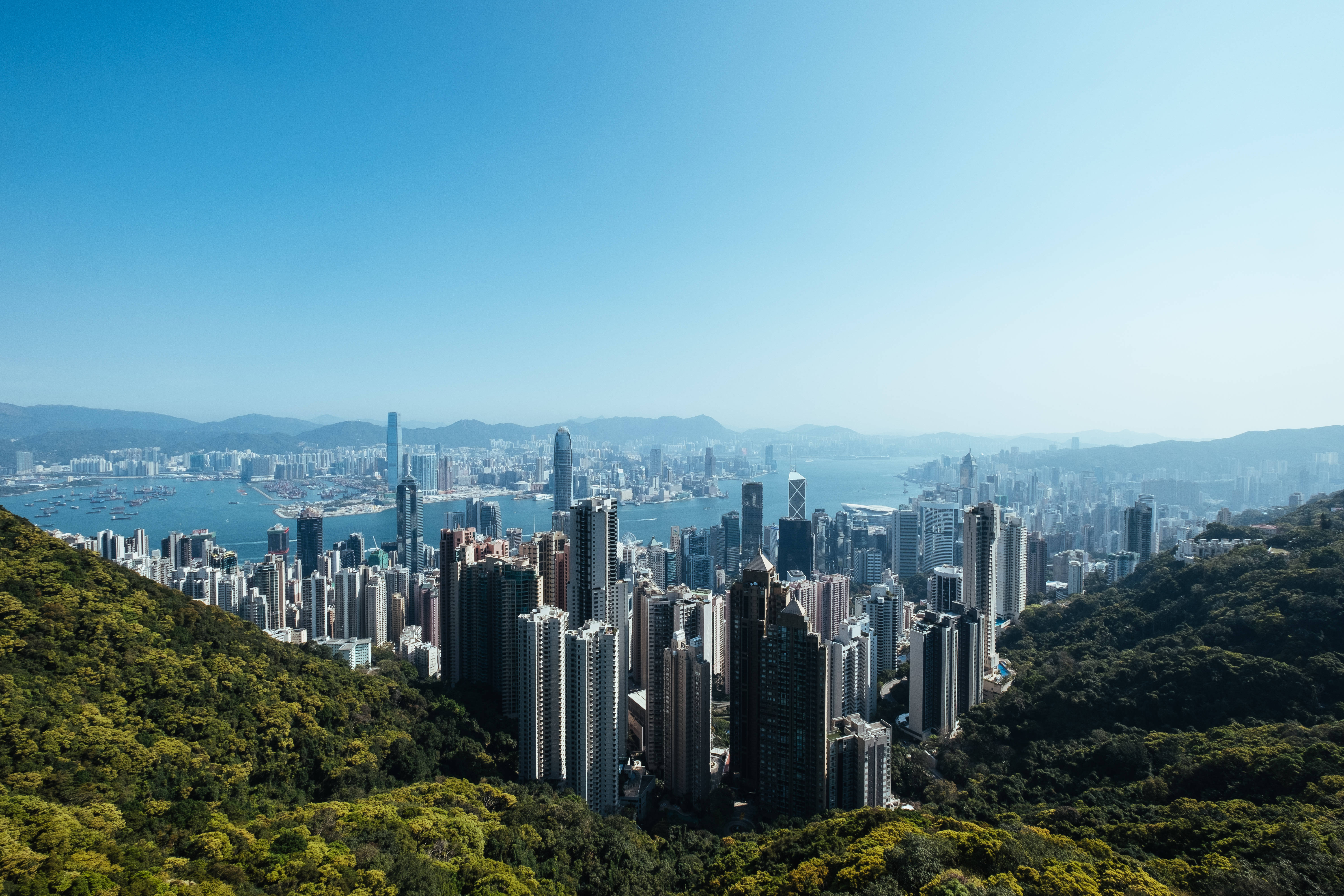 Hong Kong skyline, lush green hills, clear blue sky, 5K Desktop Wallpaper