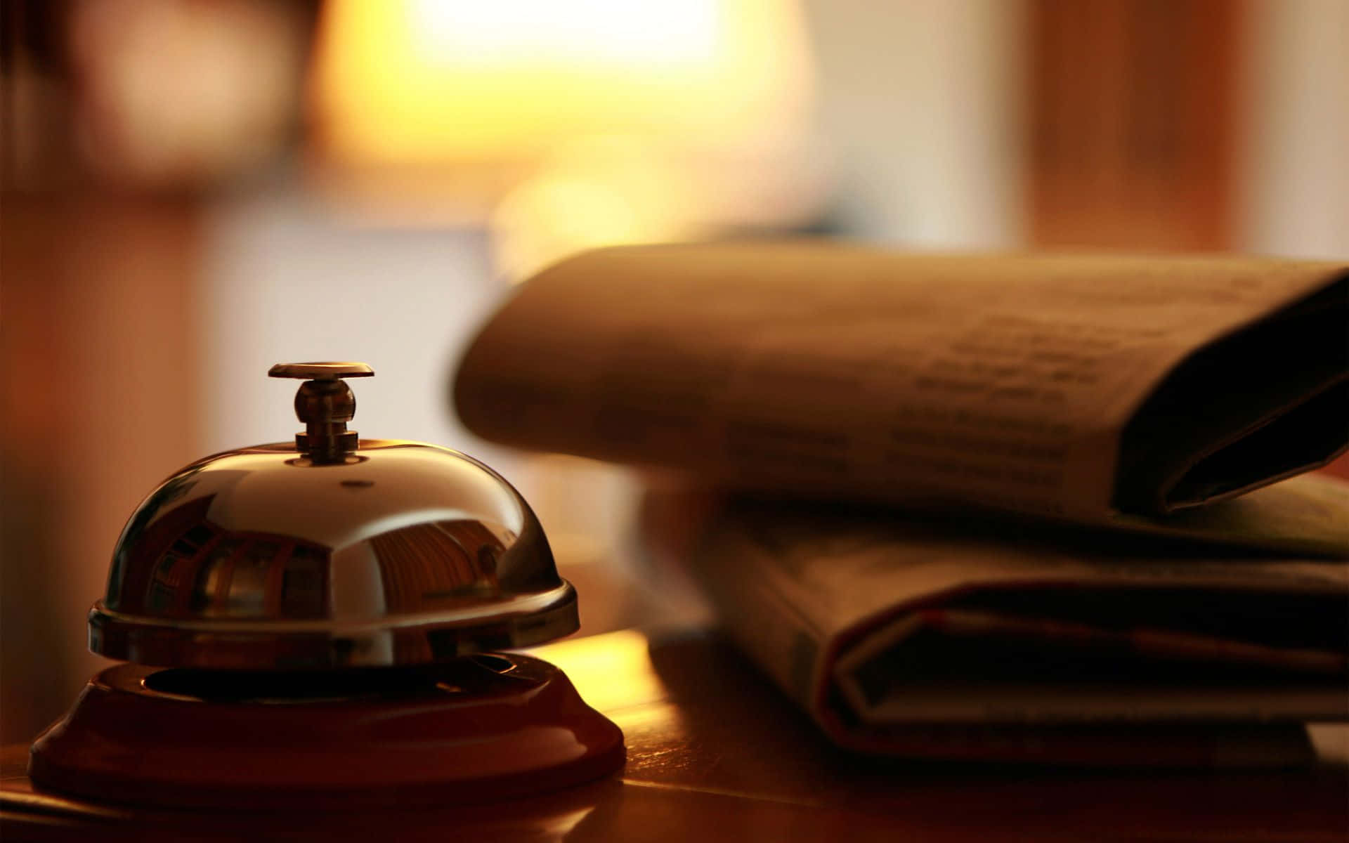 polished brass hotel service bell, stack of newspapers, wooden desk, Full HD Desktop Wallpaper