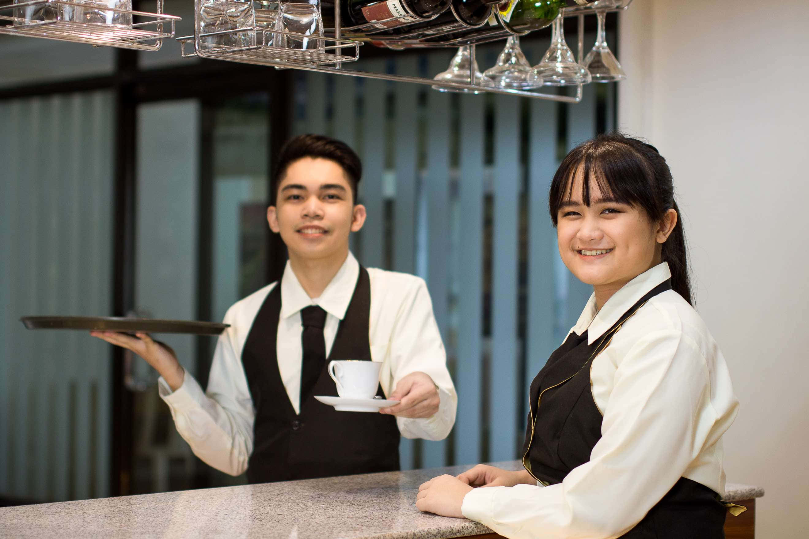 modern hotel bar, crisp uniforms, glassware hanging overhead, 2K Desktop Wallpaper