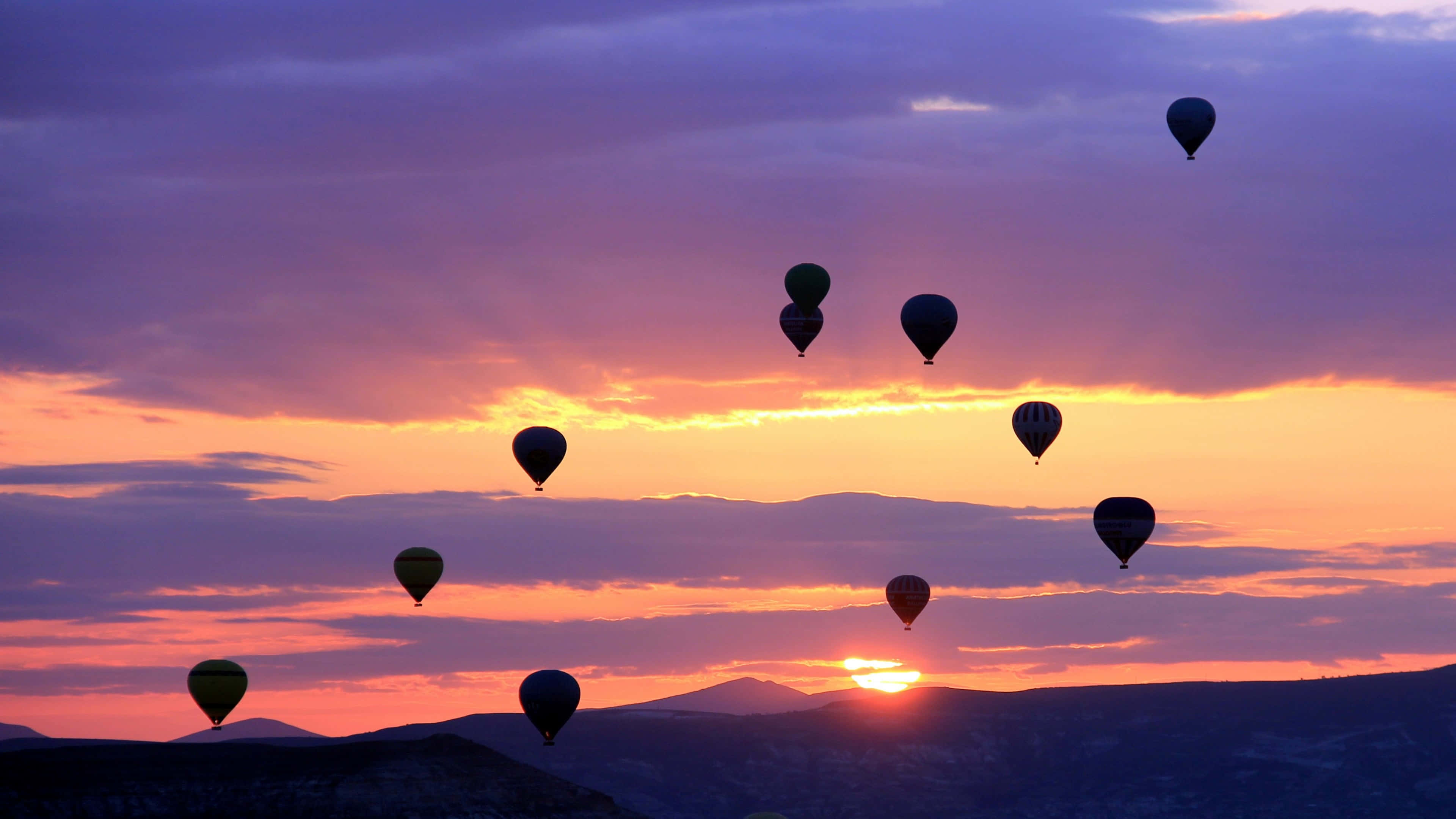 hot air balloons, vibrant purple and orange sunset, distant mountains, 4K Desktop Wallpaper