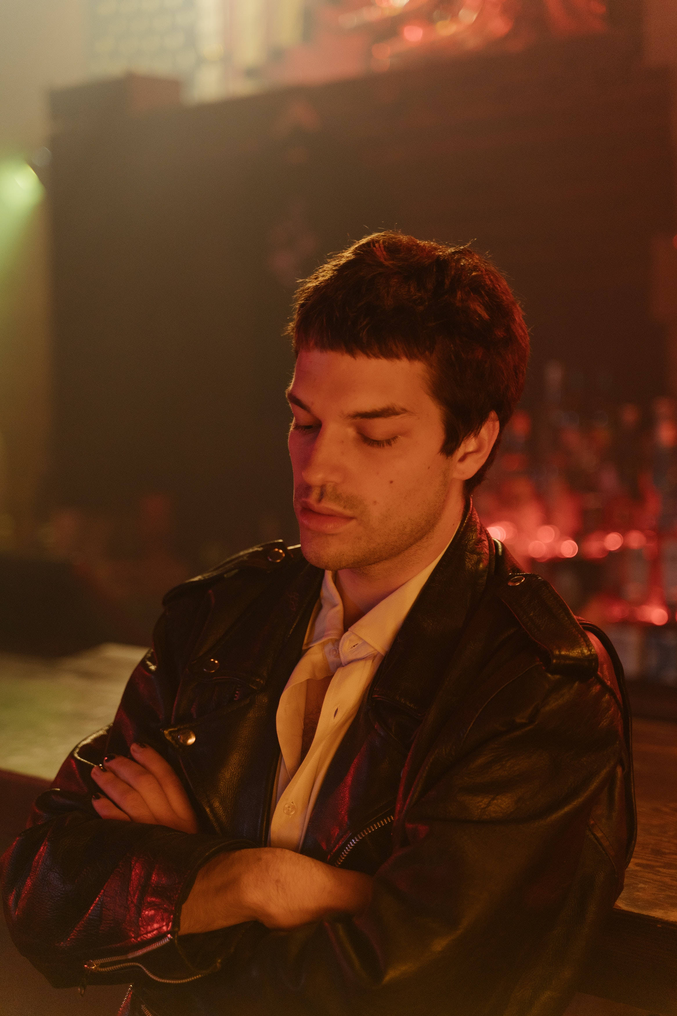black leather jacket, dimly lit bar, warm red and orange glow, 2K Phone Wallpaper
