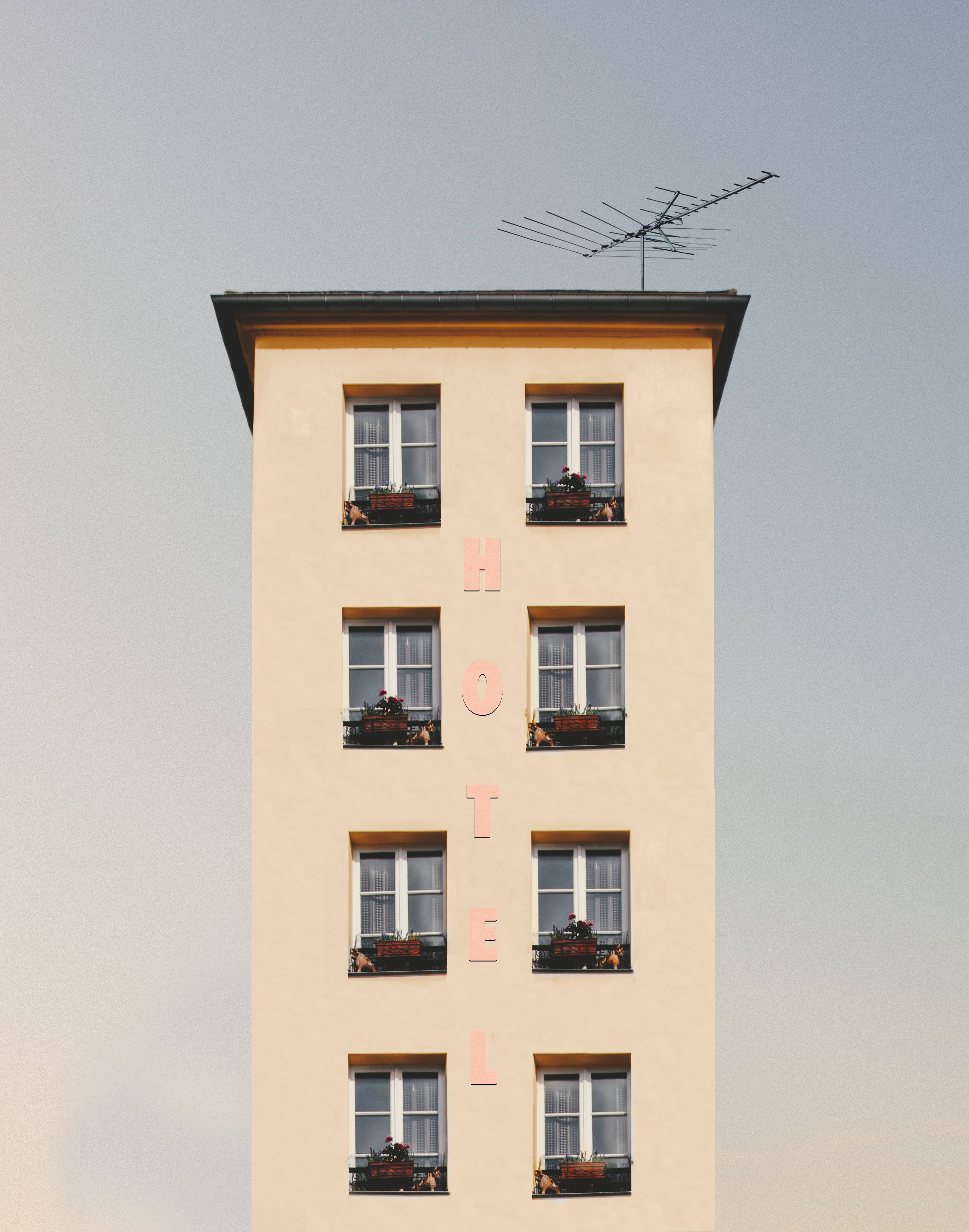 beige hotel building, vertical pink lettering, flower boxes on windows, 4K Phone Wallpaper