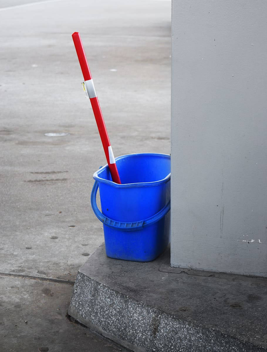 bright blue plastic bucket, red mop handle, gray concrete wall, SD Phone Wallpaper