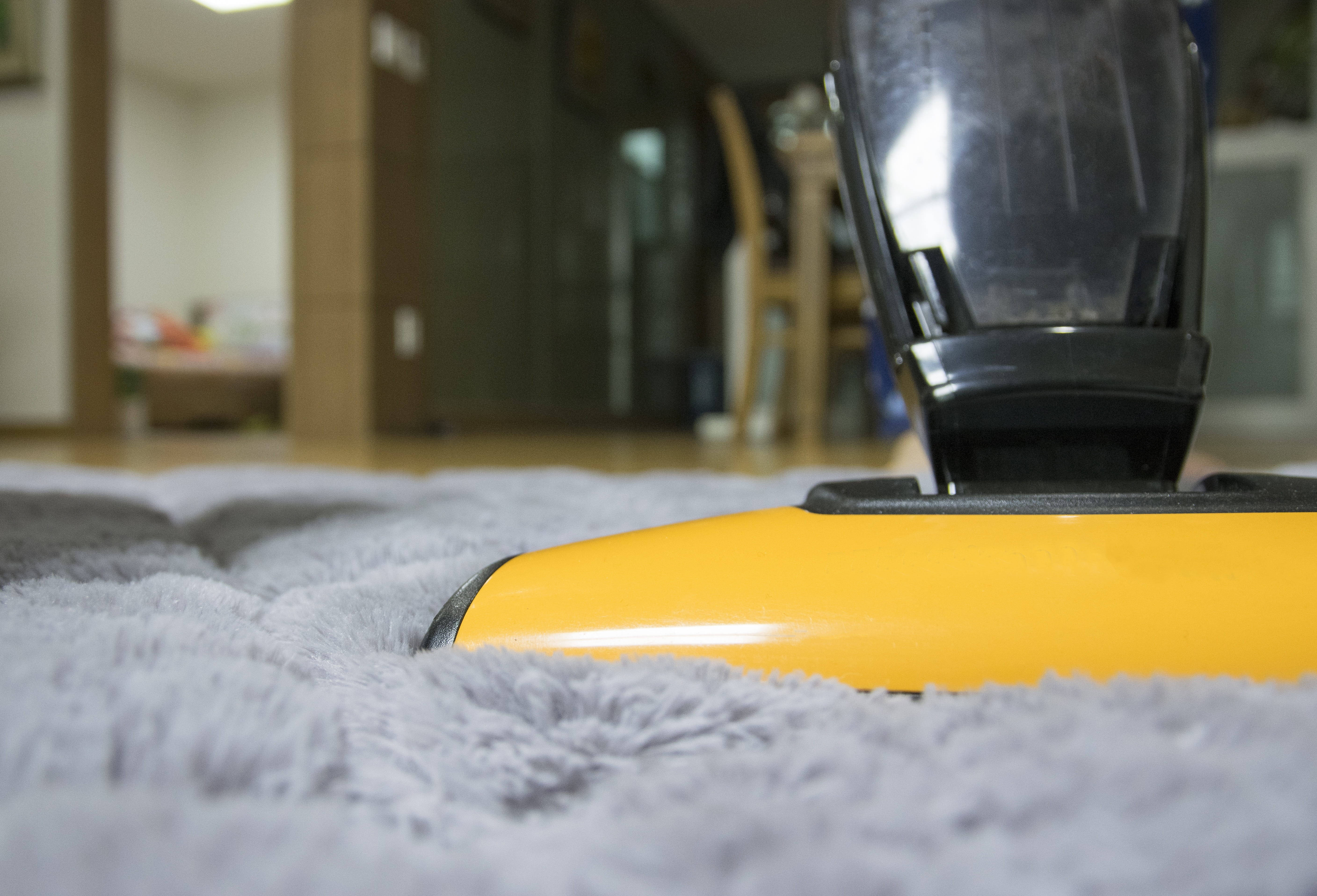 yellow vacuum cleaner head, plush gray carpet, softly lit home interior, 5K Desktop Wallpaper