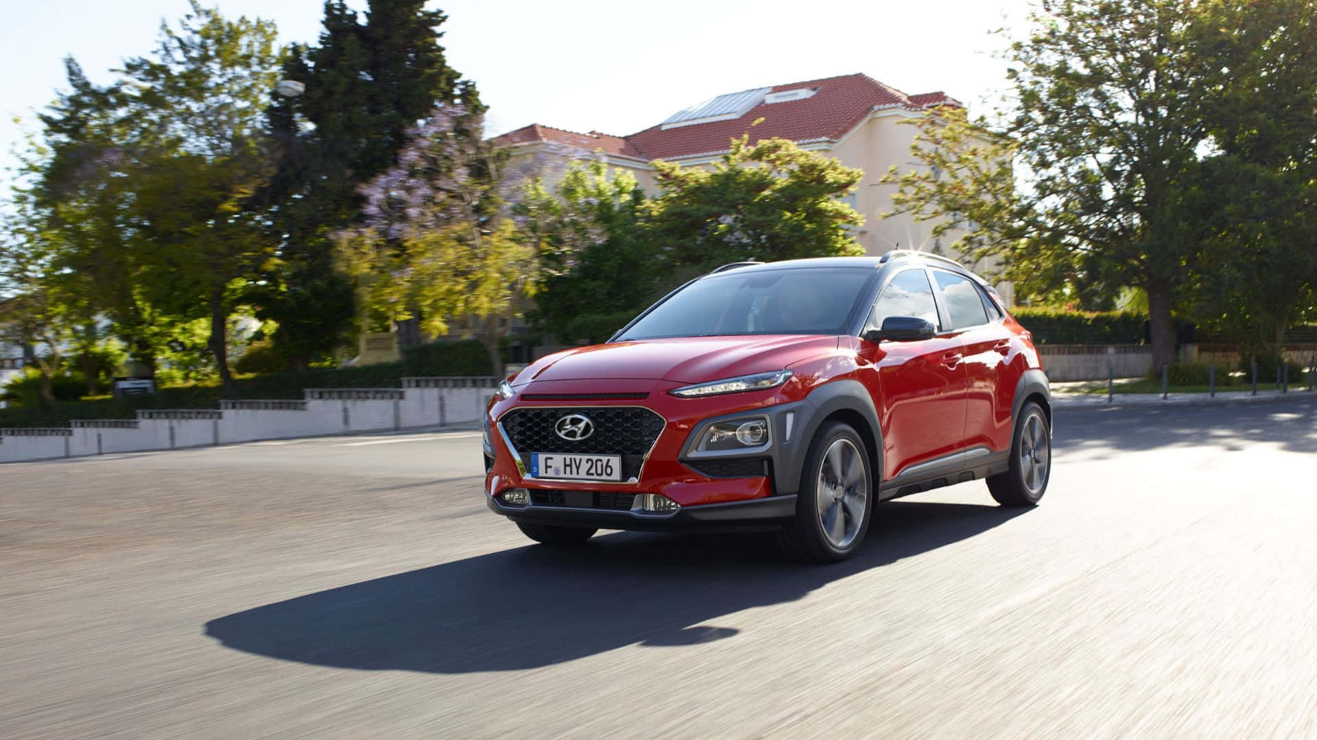 Hyundai Kona, vibrant red, sunlit tree-lined street, Full HD Desktop Wallpaper
