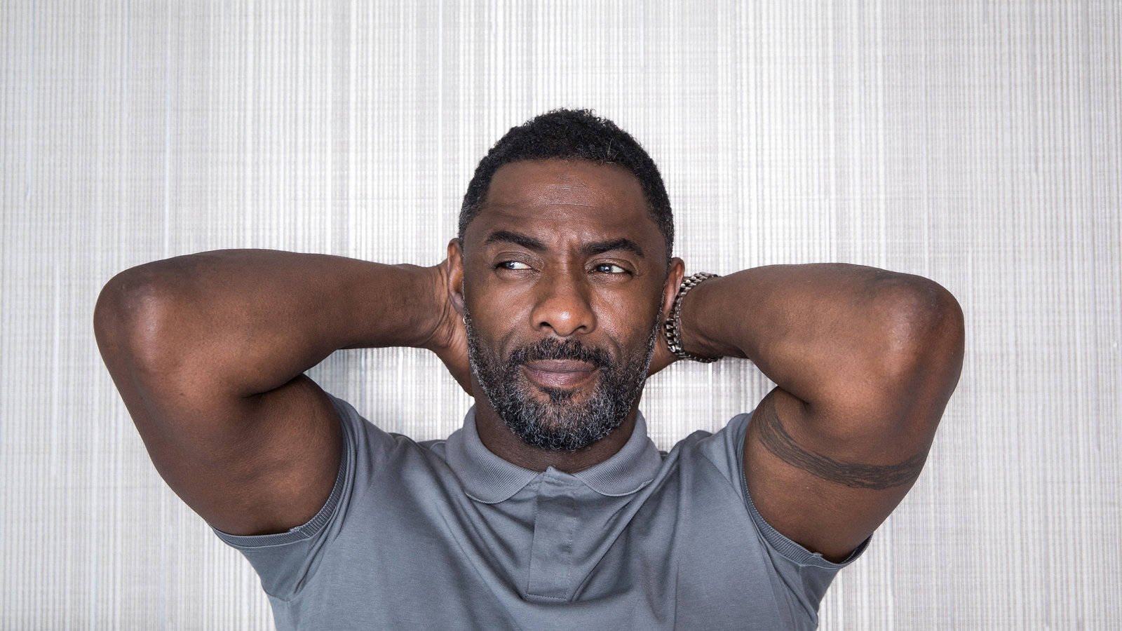 Idris Elba, hands on back of head, textured gray wall, HD Desktop Wallpaper