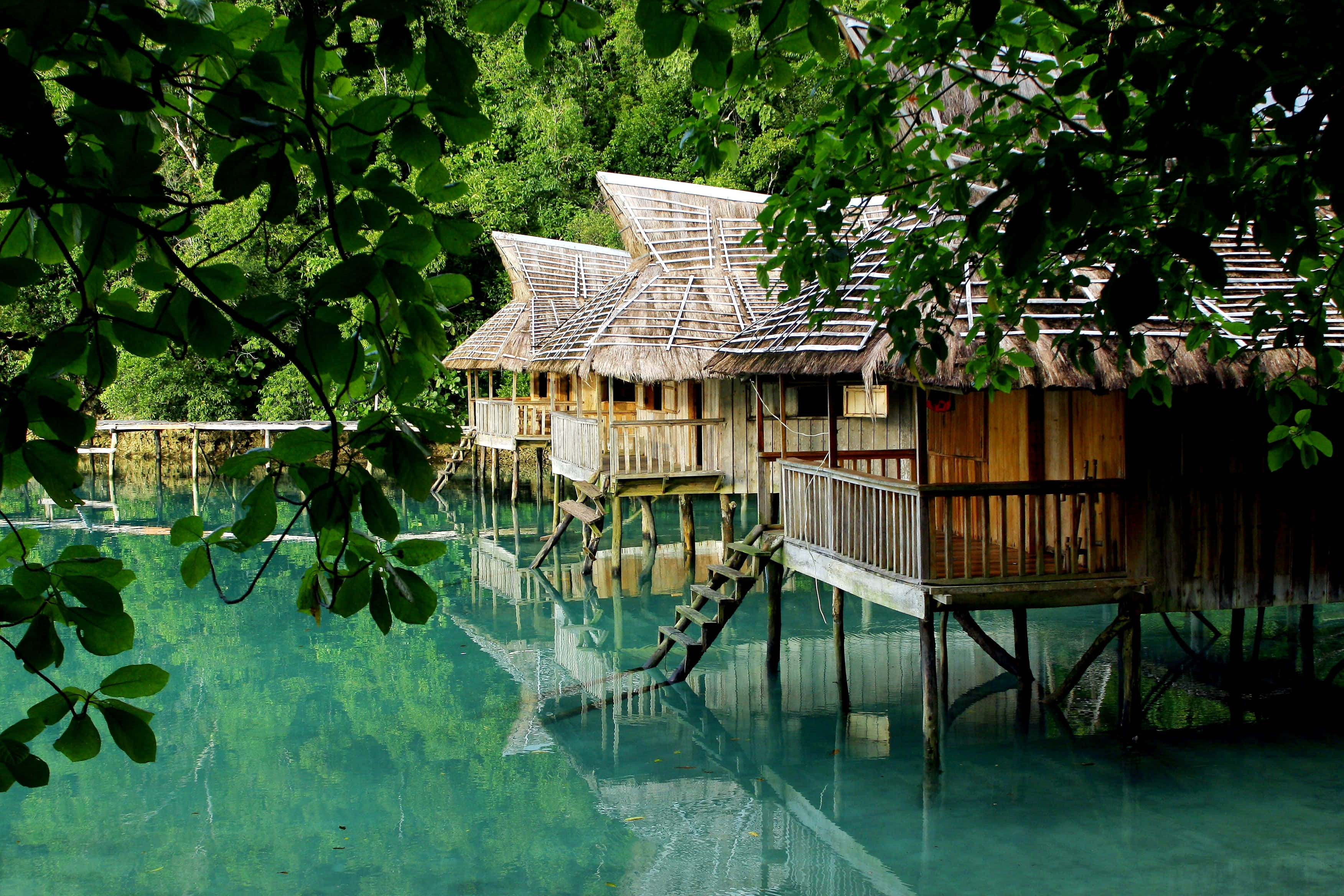 idyllic beach houses, thatched-roof stilt houses, crystal turquoise water, 2K Desktop Wallpaper