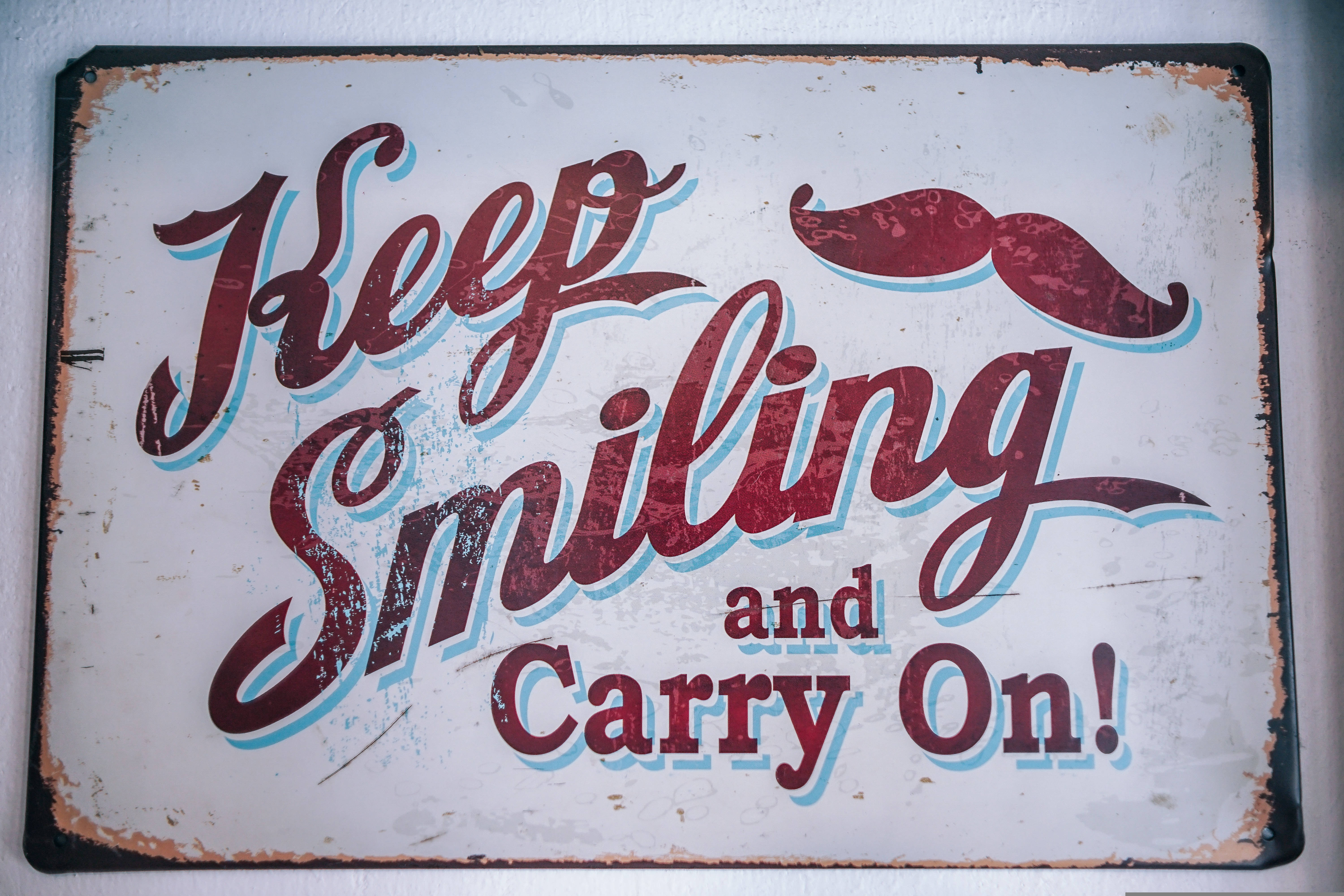 vintage weathered sign, red cursive text, Keep Smiling and Carry On!, 5K Desktop Wallpaper