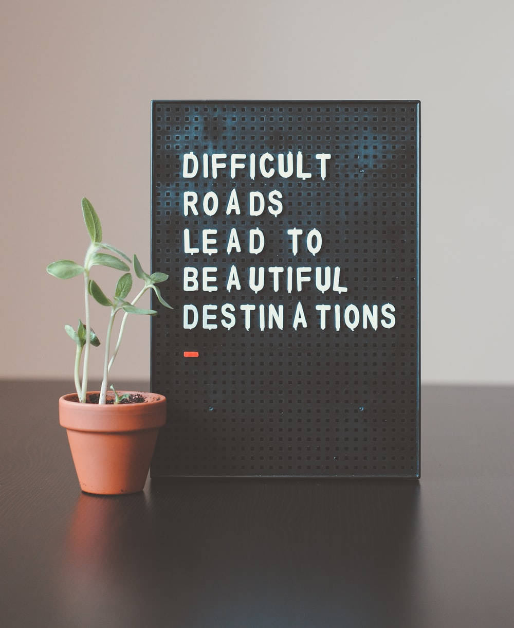 black pegboard sign, motivational phrase difficult roads lead to beautiful destinations, small potted plant, SD Phone Wallpaper