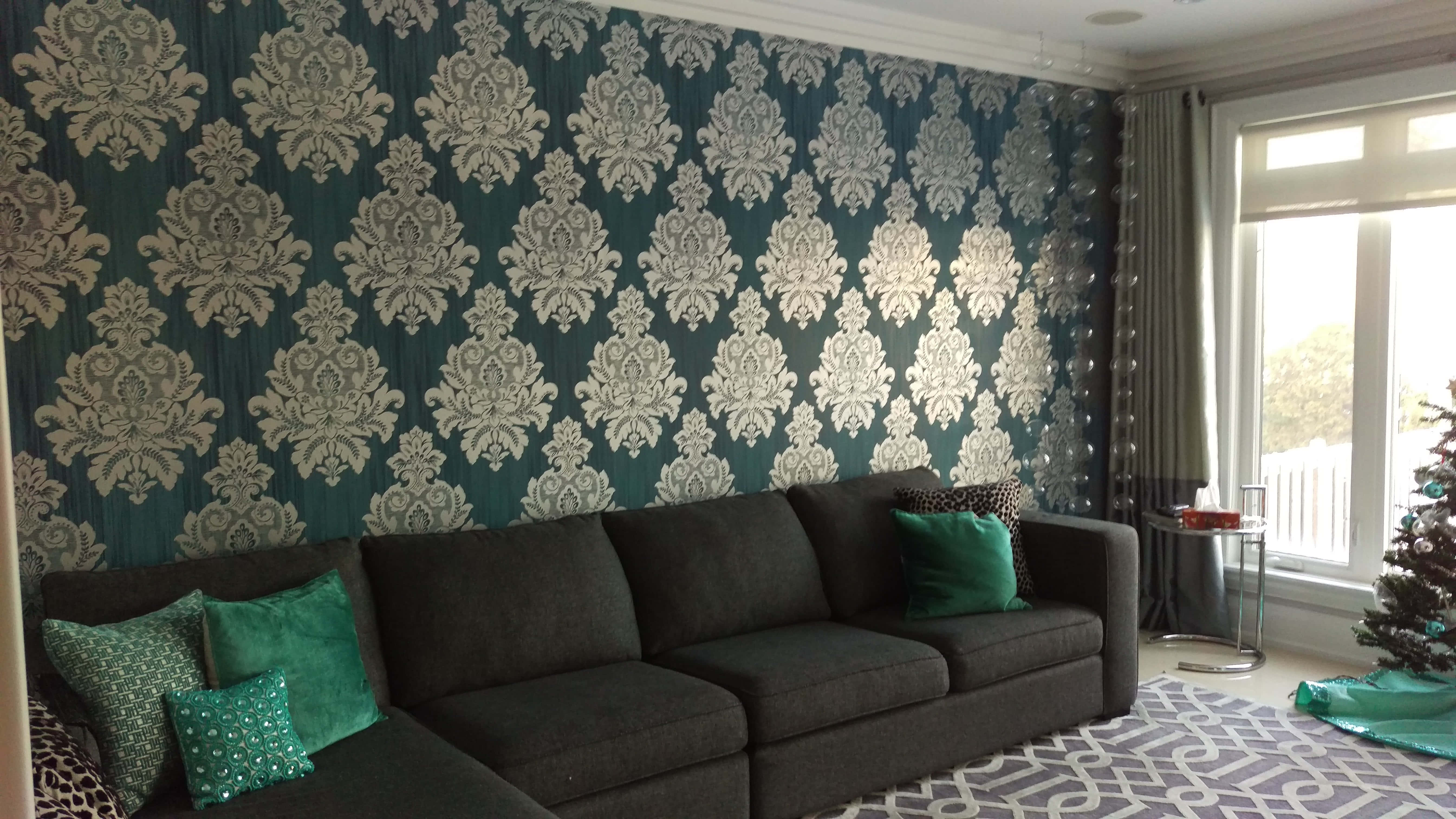 teal and silver damask wallpaper, dark sofa with green pillows, sunlit living room, 5K Desktop Wallpaper