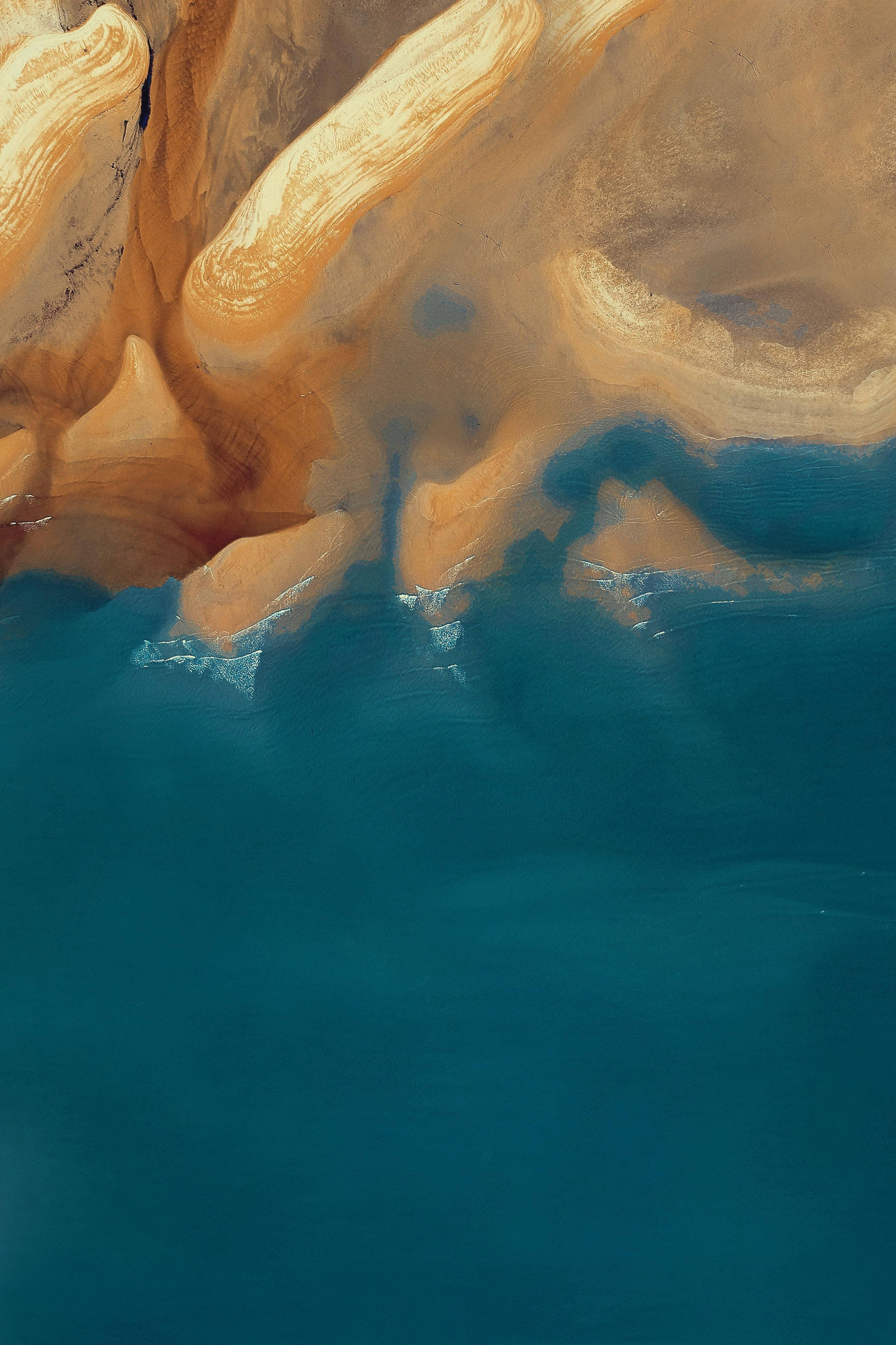iPhone 13, golden sandstone cliffs, deep teal ocean waters, 4K Phone Wallpaper