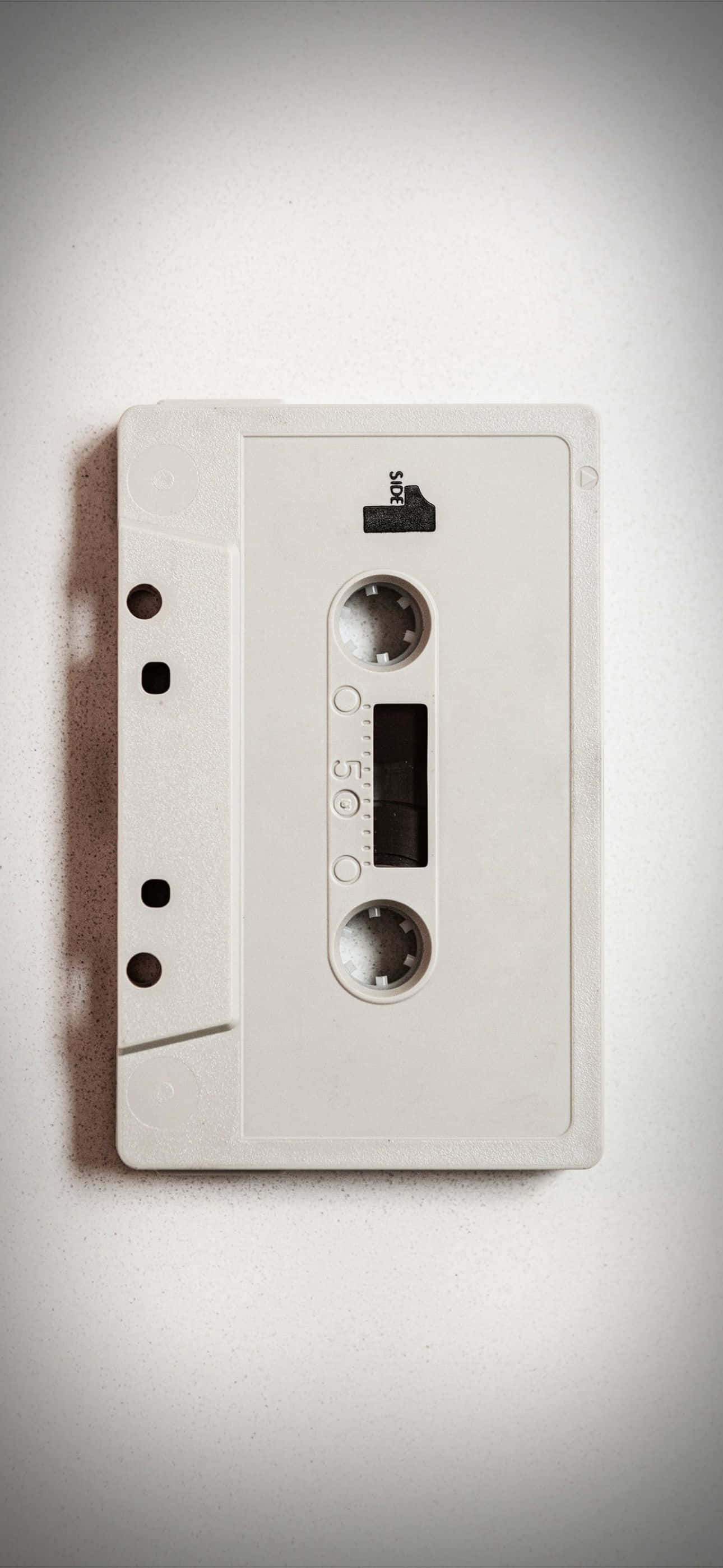iPhone 14 Pro Max, vintage white cassette tape, plain light gray surface, 2K Phone Wallpaper