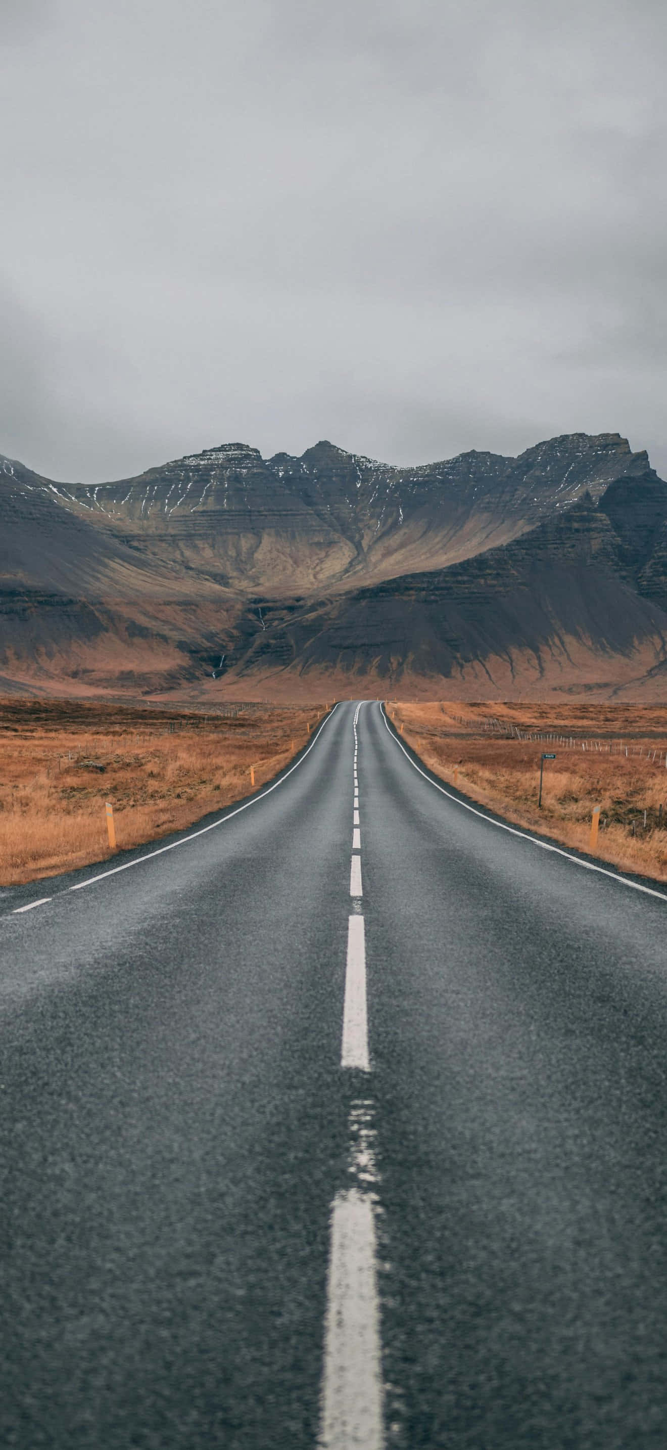 iPhone 17 Pro Max, asphalt road, snow-dusted mountains, 2K Phone Wallpaper