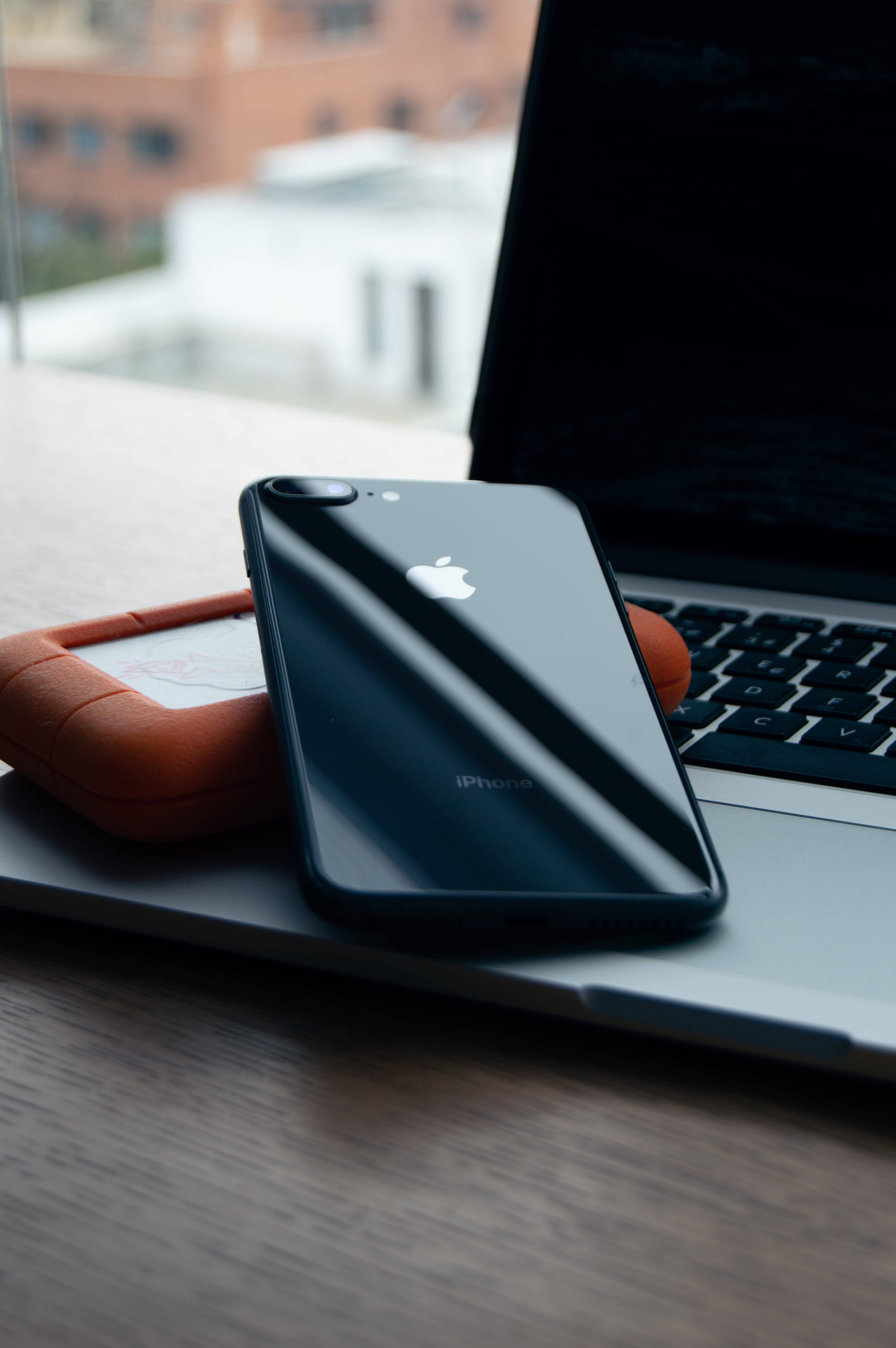black iPhone, silver laptop, orange case, 5K Phone Wallpaper