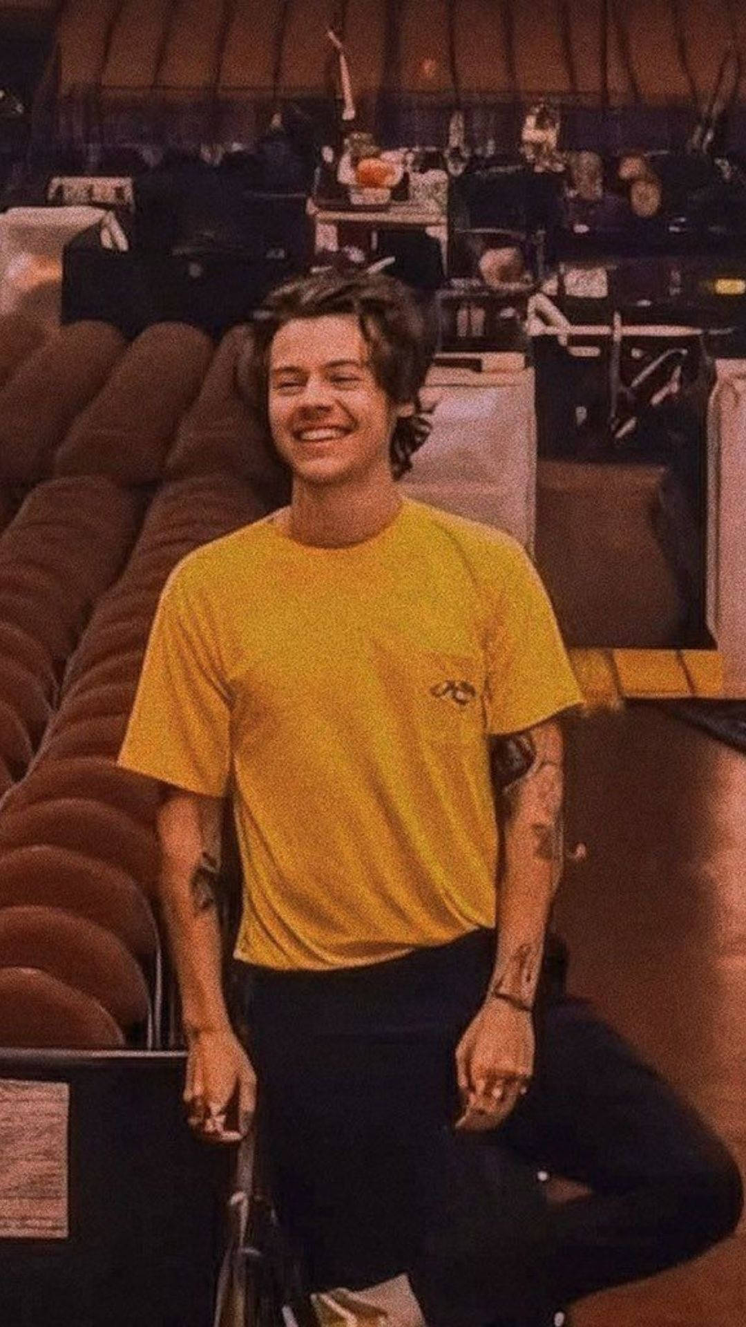 iPhone Harry Styles, yellow tshirt, brown theater seats, Full HD Phone Wallpaper