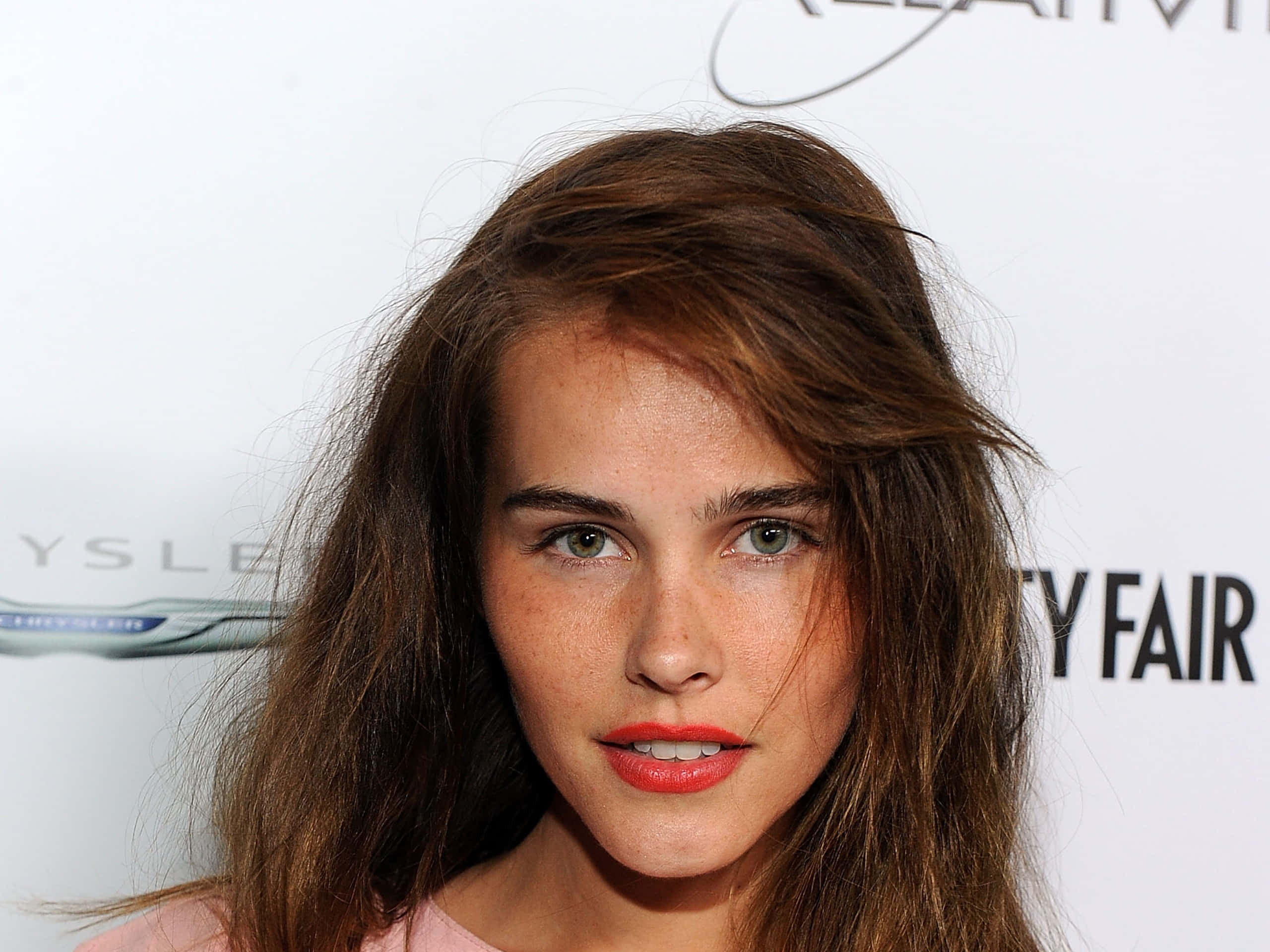Isabel Lucas, branded event backdrop, tousled brown hair, 2K Desktop Wallpaper