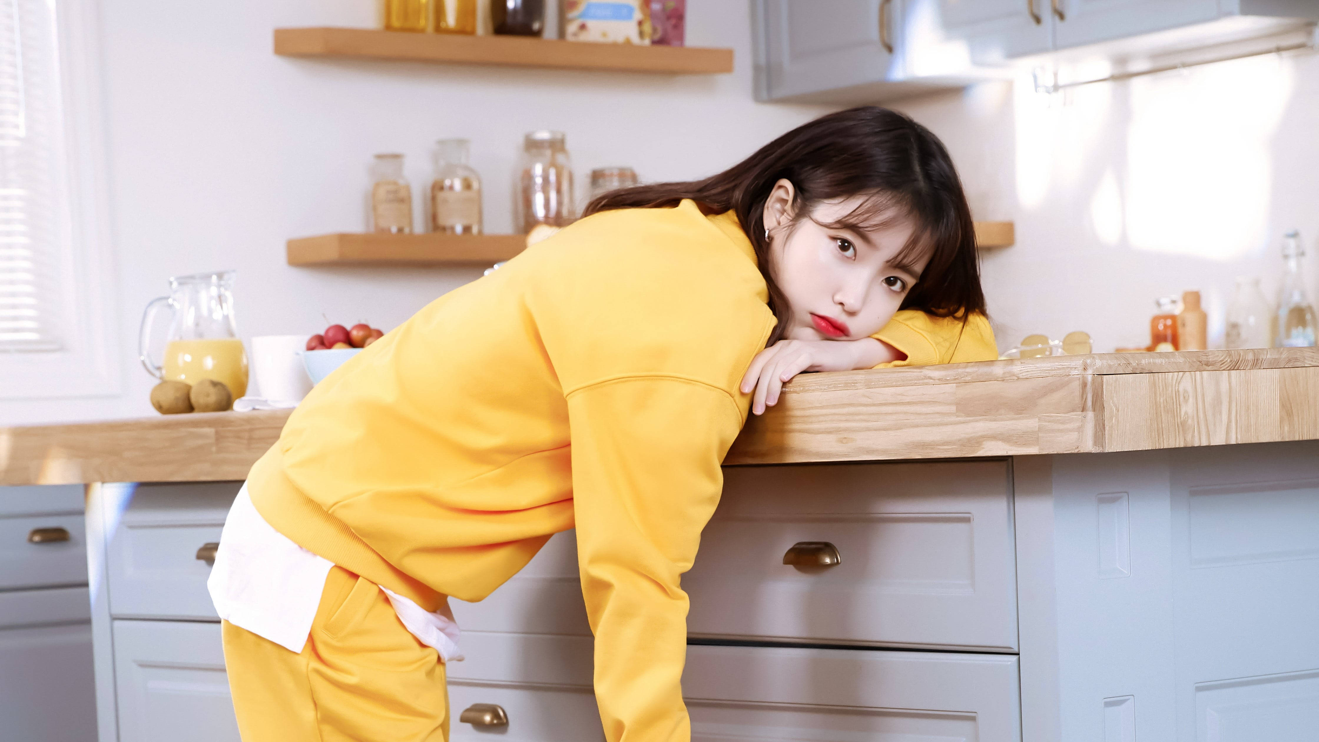 IU, bright yellow tracksuit, wooden kitchen counter, 4K Desktop Wallpaper
