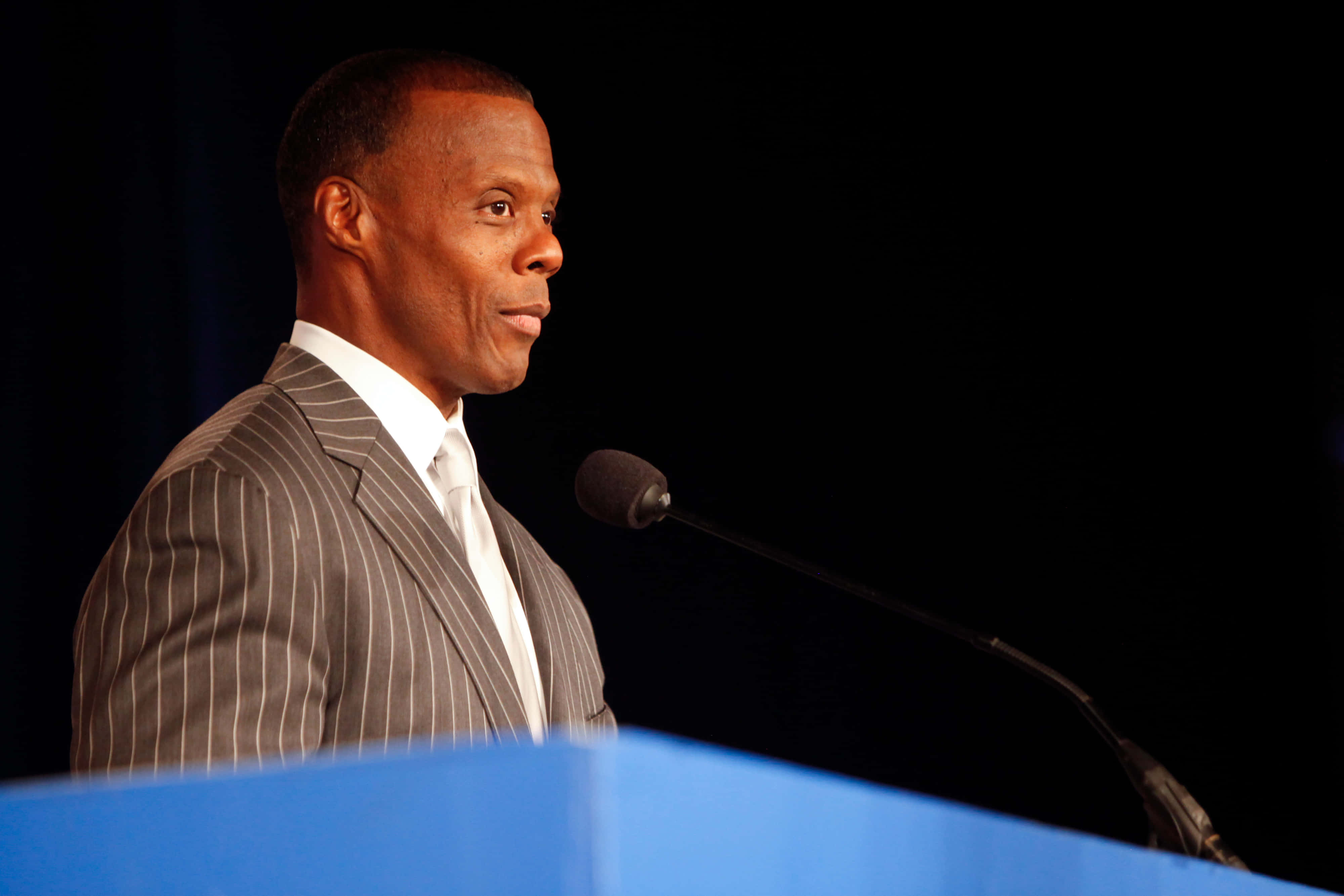 J.C. Watts, pinstripe suit, blue podium, 4K Desktop Wallpaper