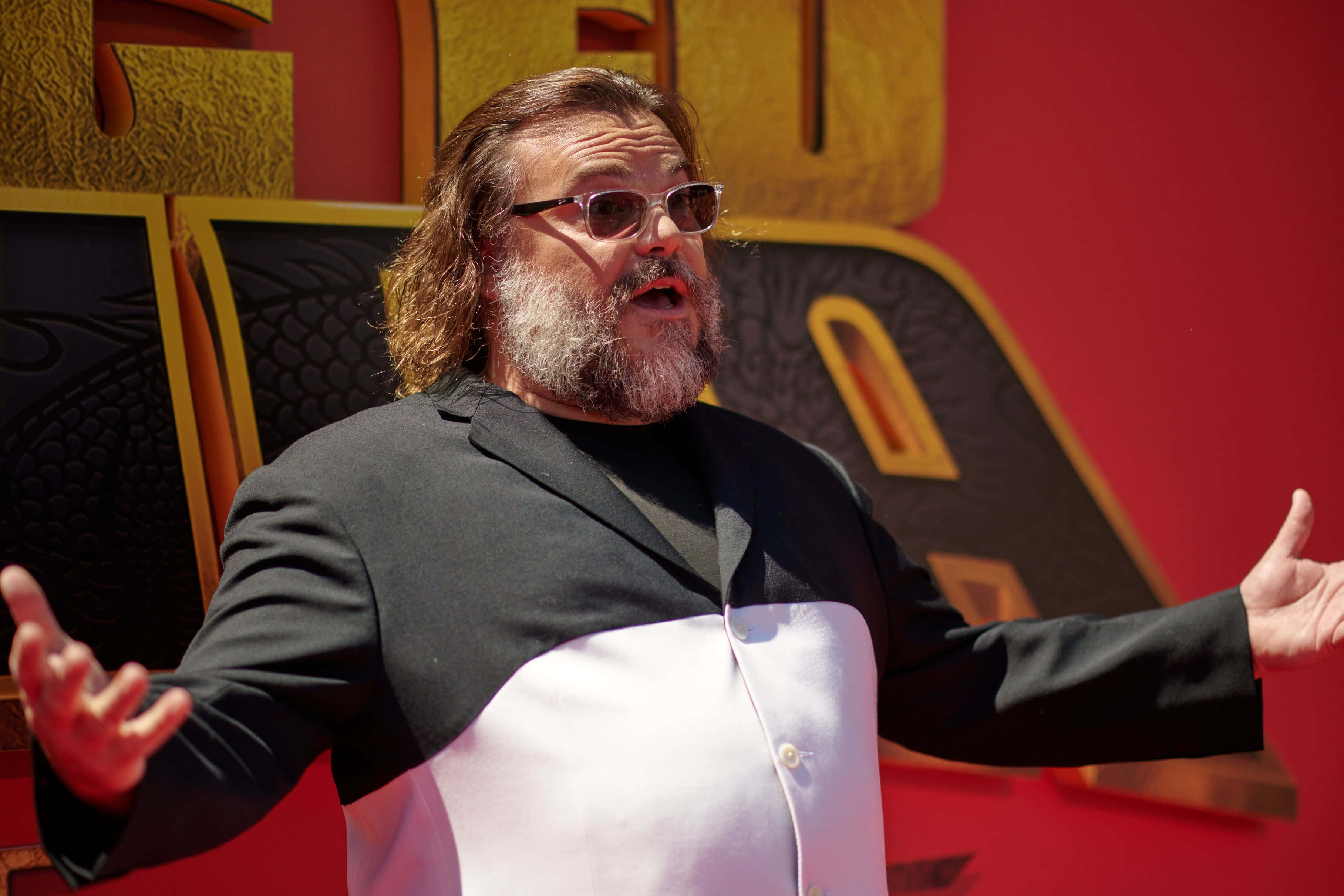 Jack Black, black-and-white jacket, red and gold backdrop, 2K Desktop Wallpaper