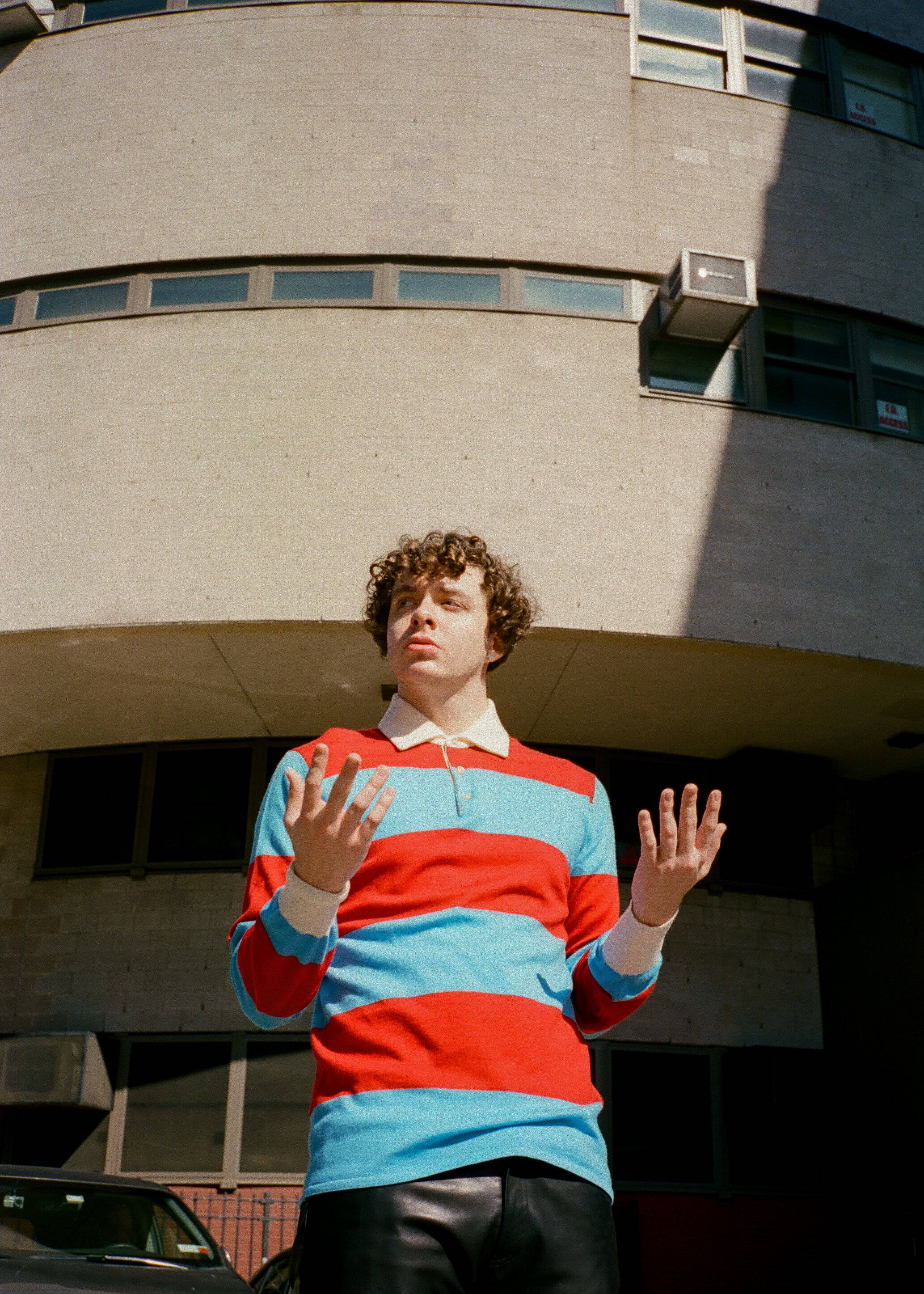 Jack Harlow, red and blue striped polo shirt, curved beige building, 2K Phone Wallpaper