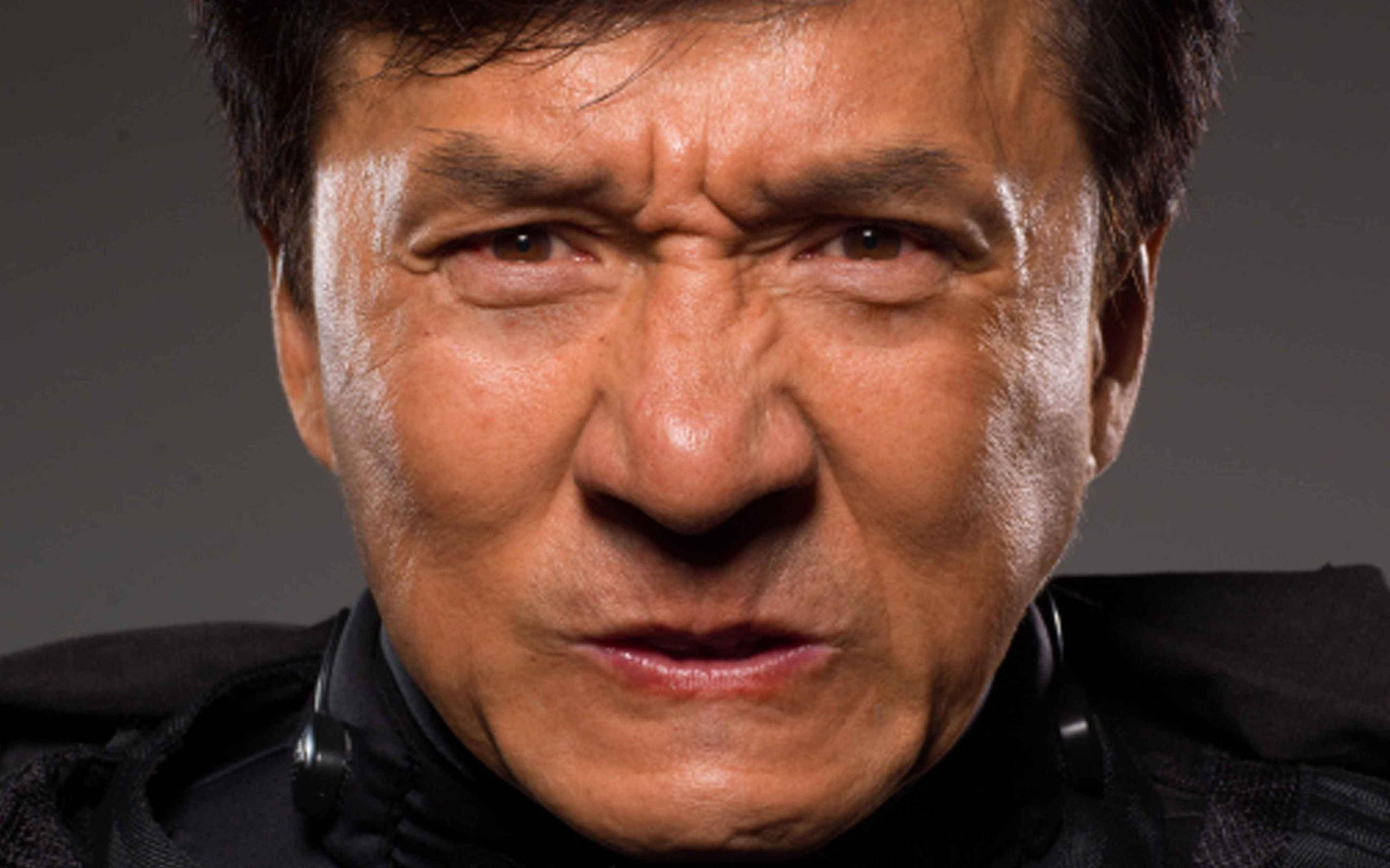 Jackie Chan, intense focused expression, dark gray background, 2K Desktop Wallpaper