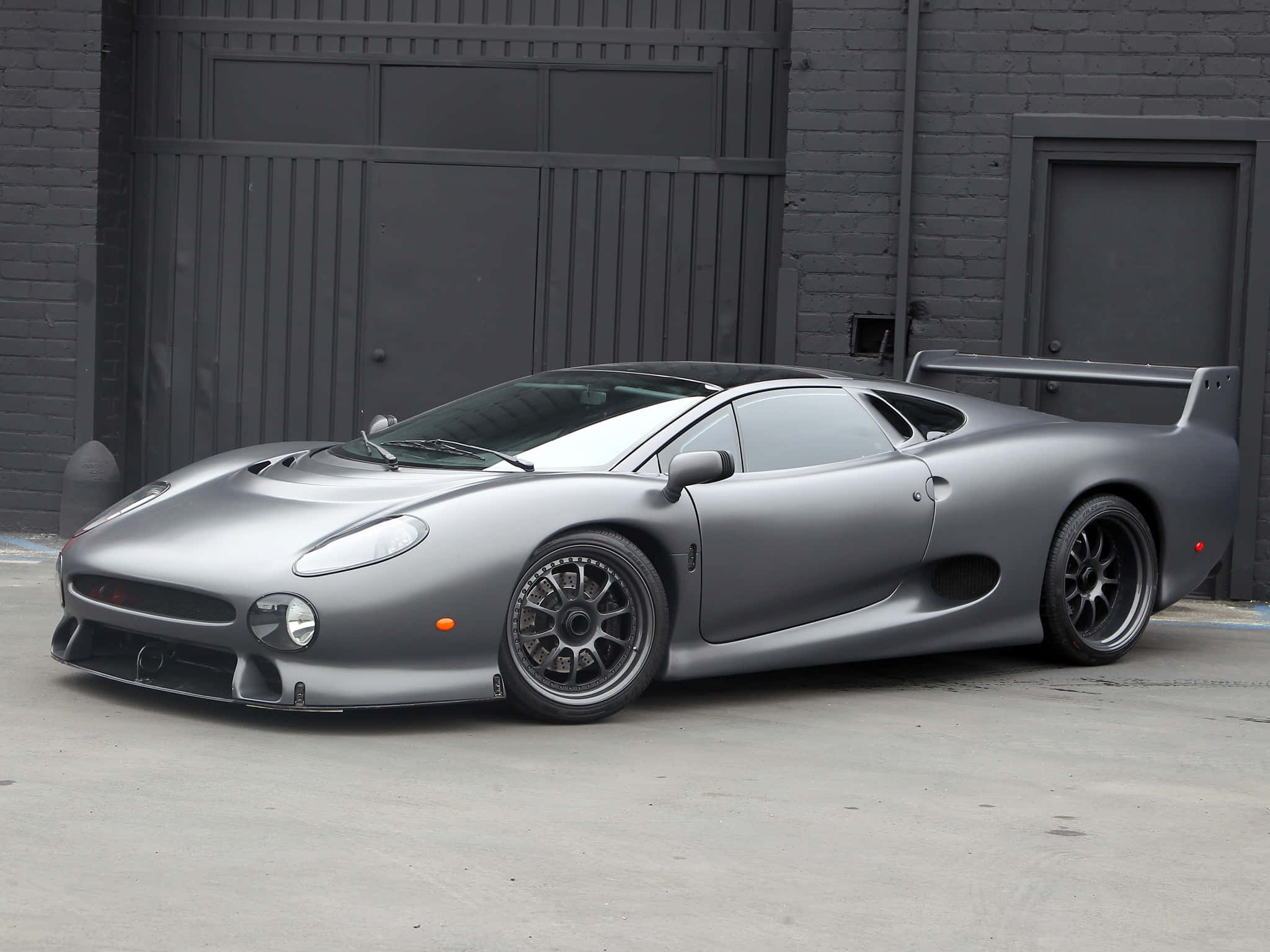 Jaguar XJ220, matte silver, dark gray brick building, Full HD Desktop Wallpaper