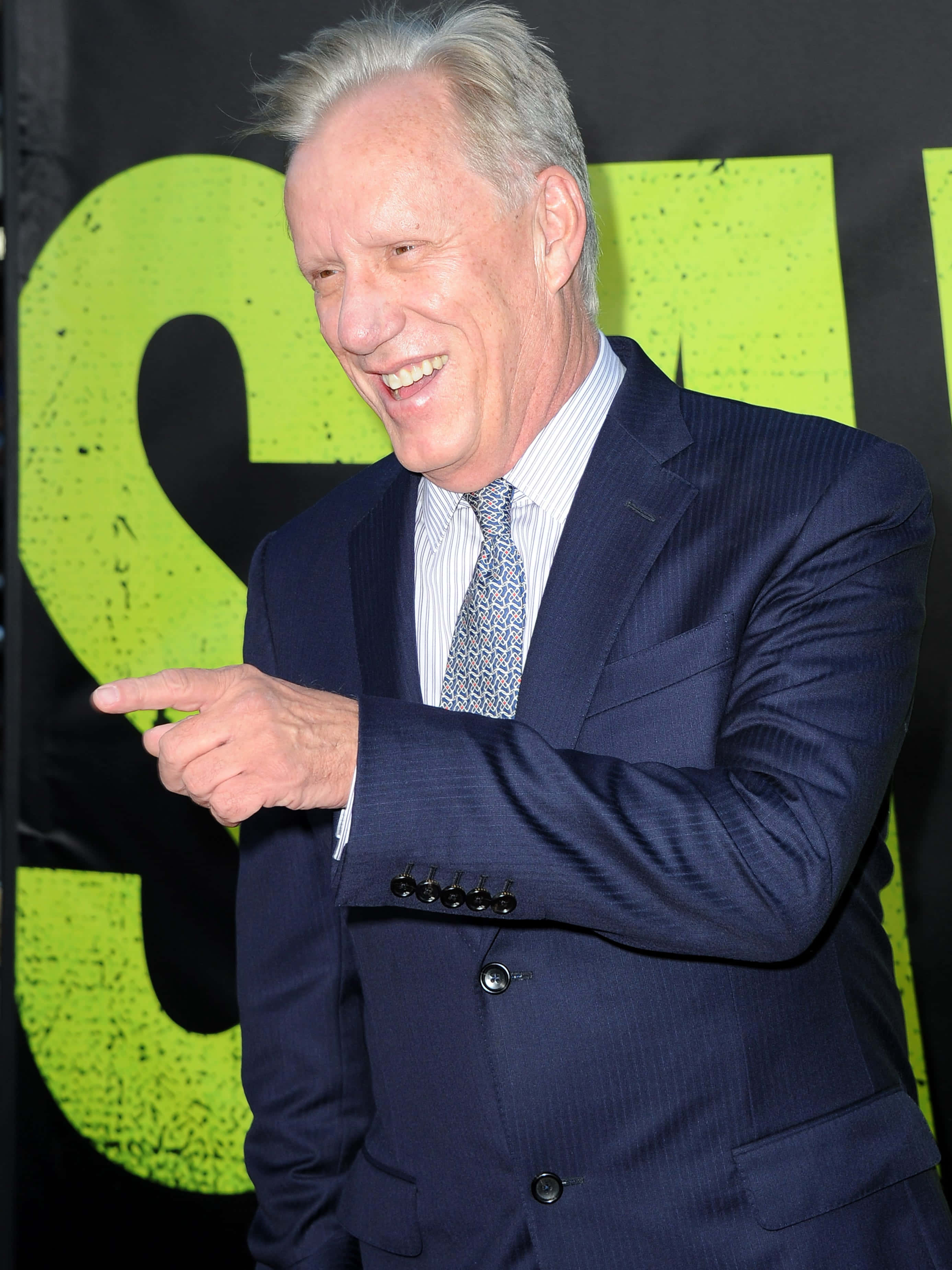 James Woods, navy suit, bright green graphic backdrop, 2K Phone Wallpaper