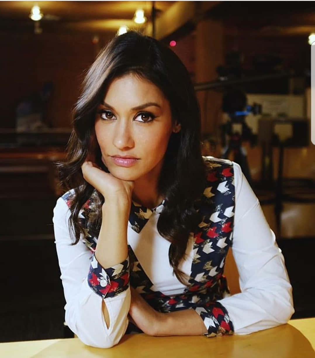 Janina Gavankar, dark wavy hair, wooden table, SD Phone Wallpaper