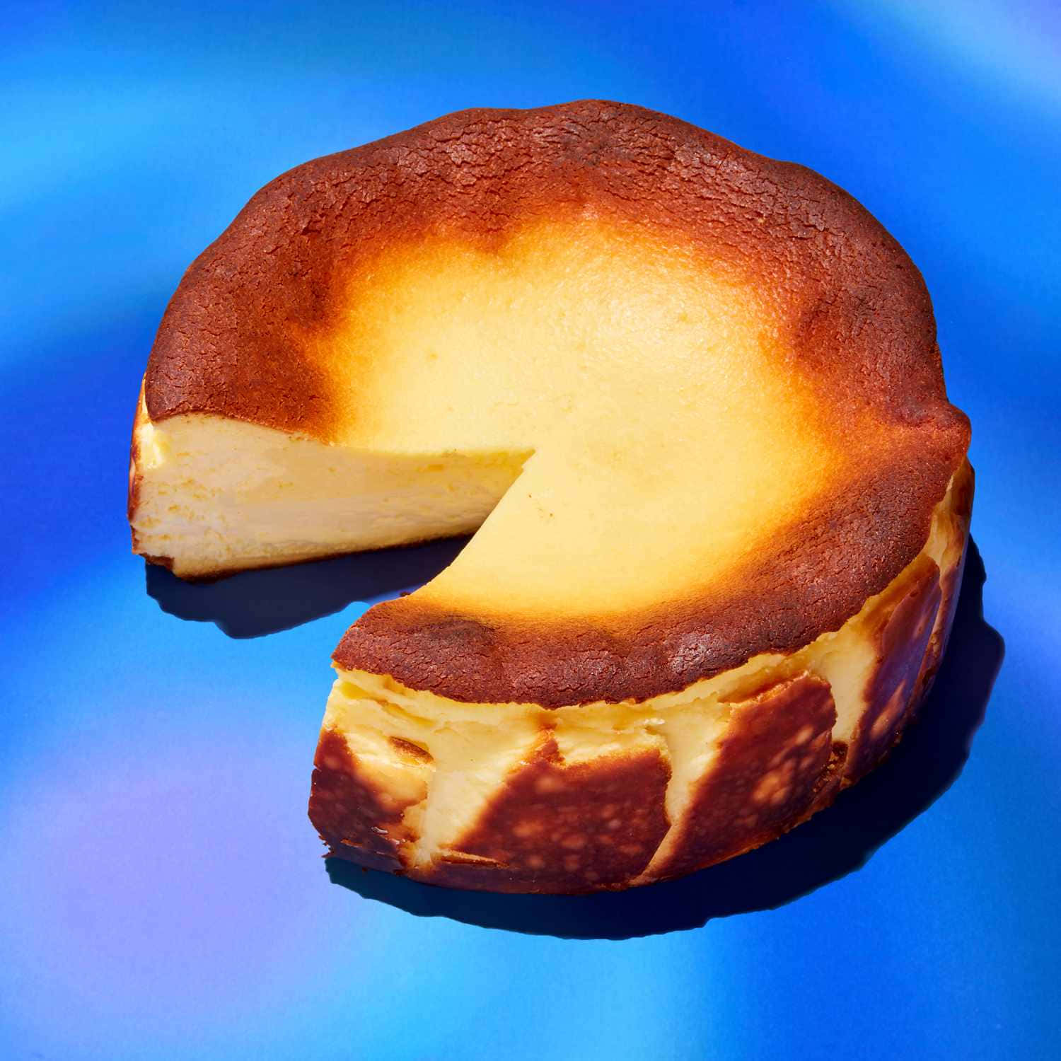 golden-brown baked cheesecake, vibrant blue surface, slice removed, HD Desktop Wallpaper