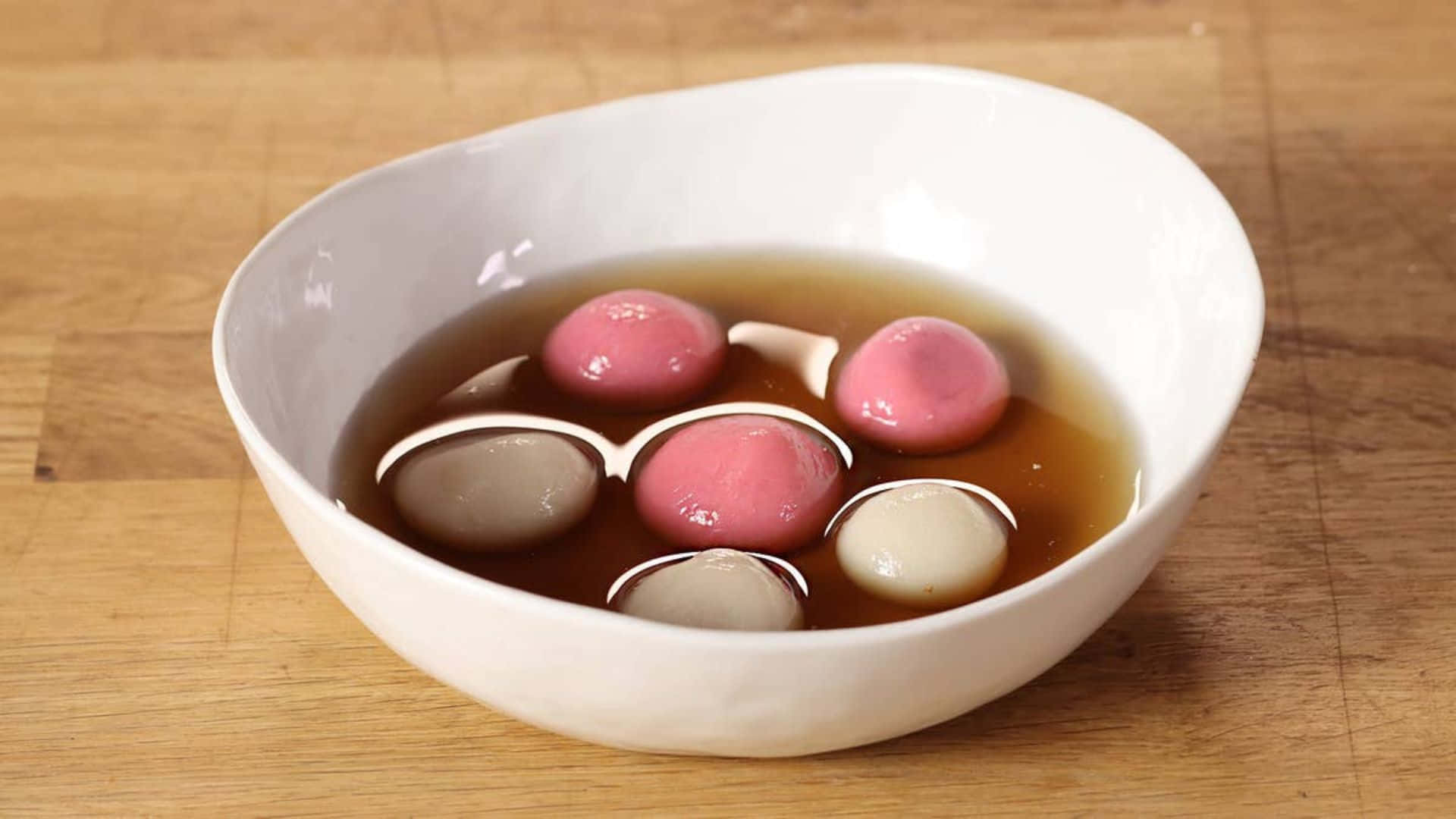 traditional tangyuan dessert, glossy pink and beige round dumplings, dark brown broth, Full HD Desktop Wallpaper