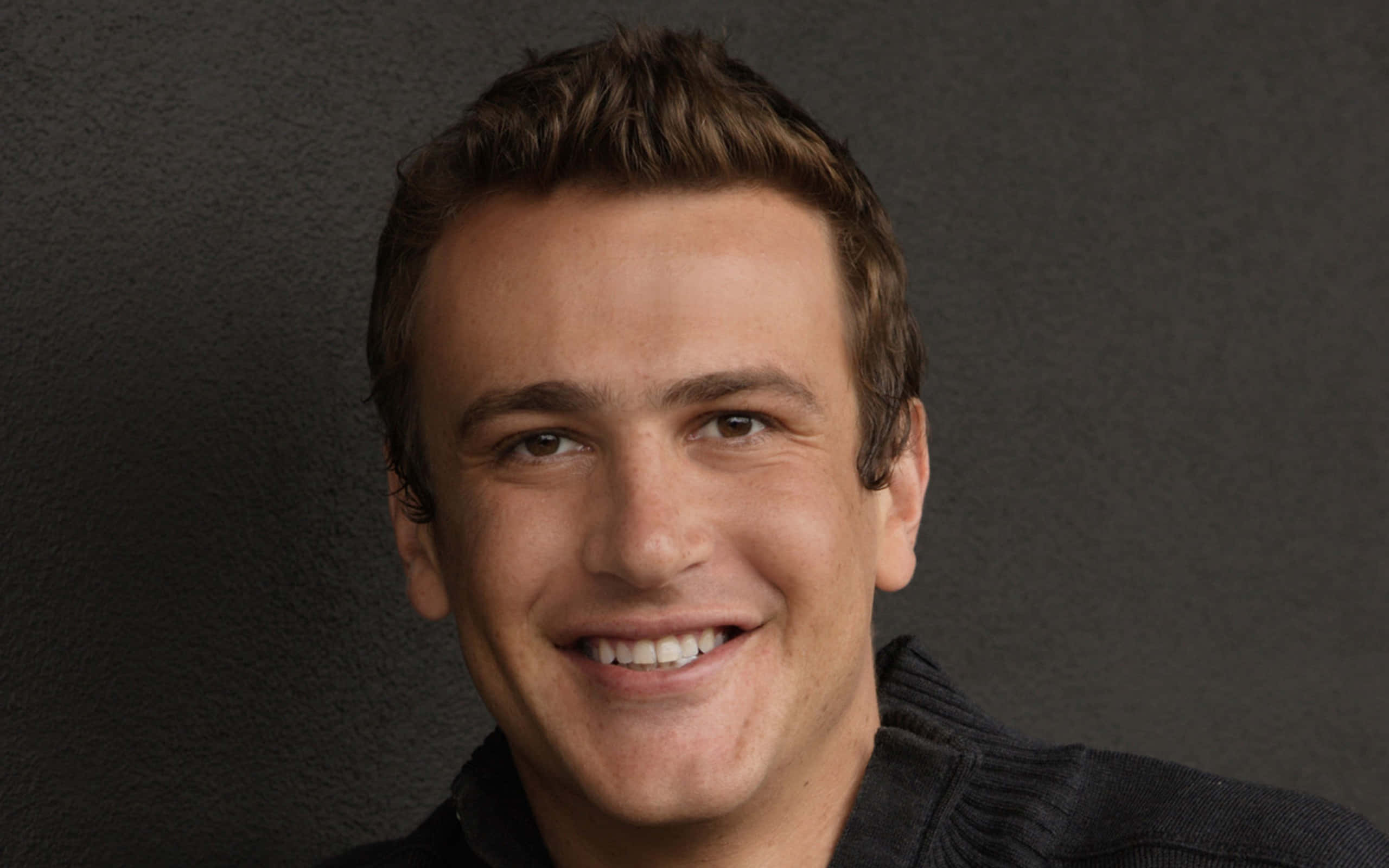 Jason Segel, short brown hair, dark textured background, 2K Desktop Wallpaper