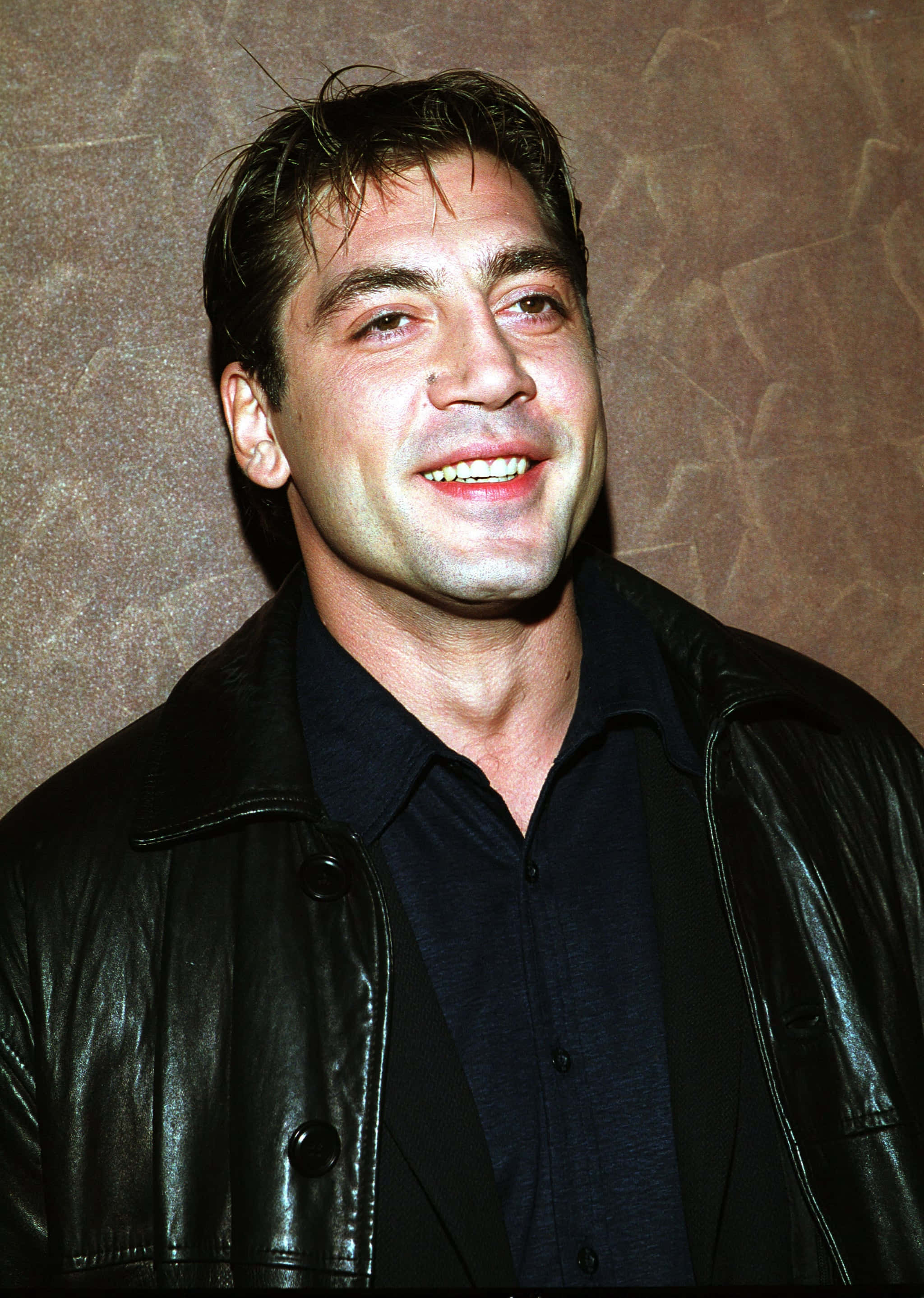 Javier Bardem, black leather jacket, textured brown wall, 2K Phone Wallpaper