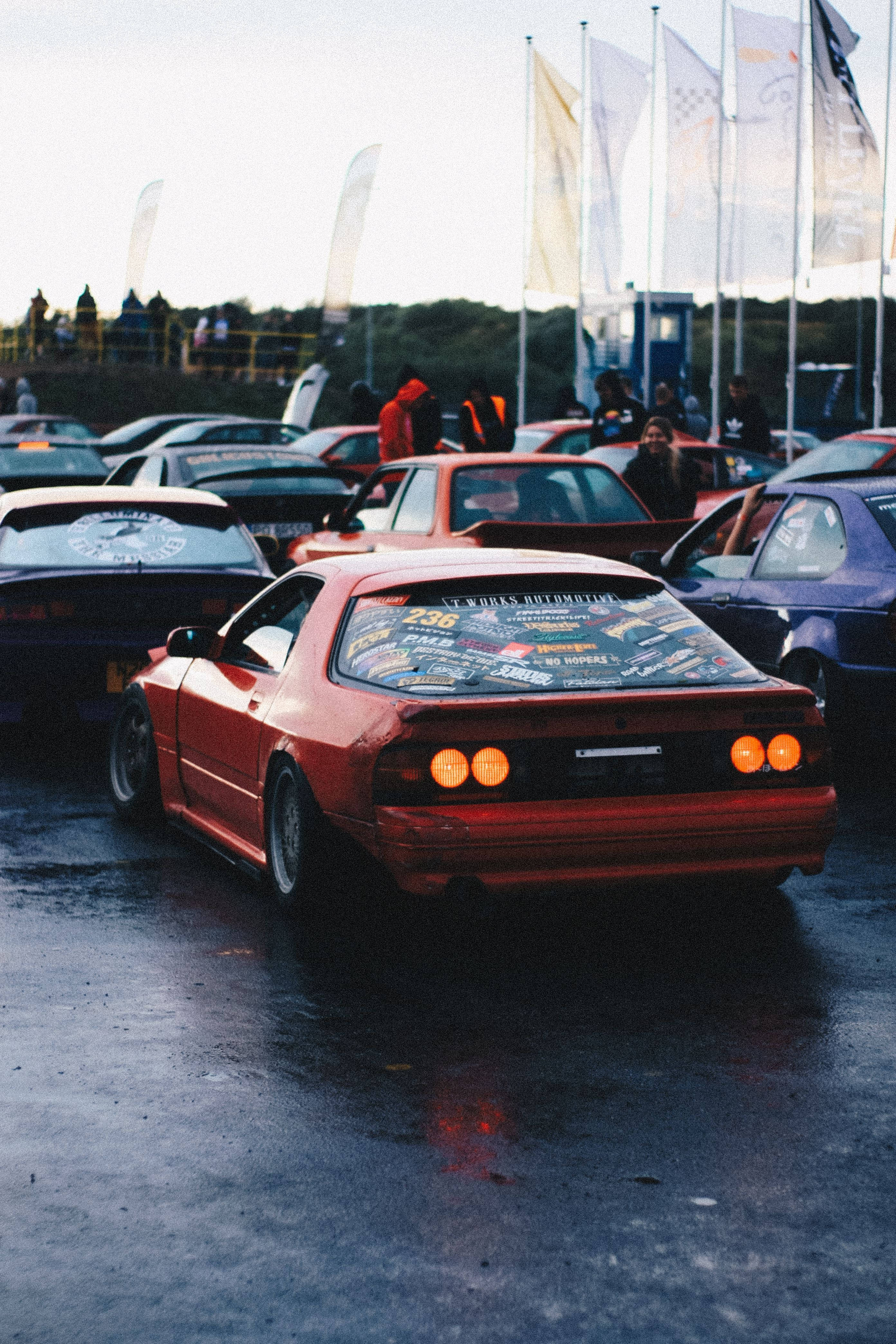 red JDM car, glowing taillights, wet asphalt lot, 4K Phone Wallpaper