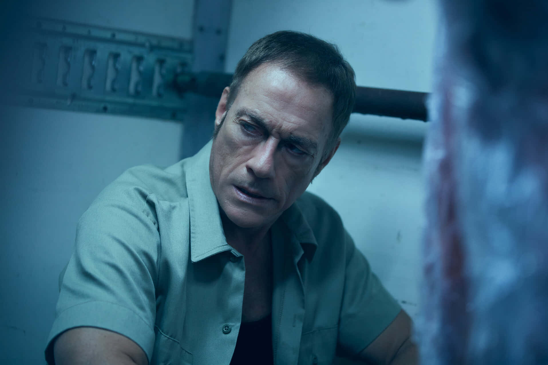 Jean Claude Van Damme, prison uniform, dim blue-lit cell, HD Desktop Wallpaper