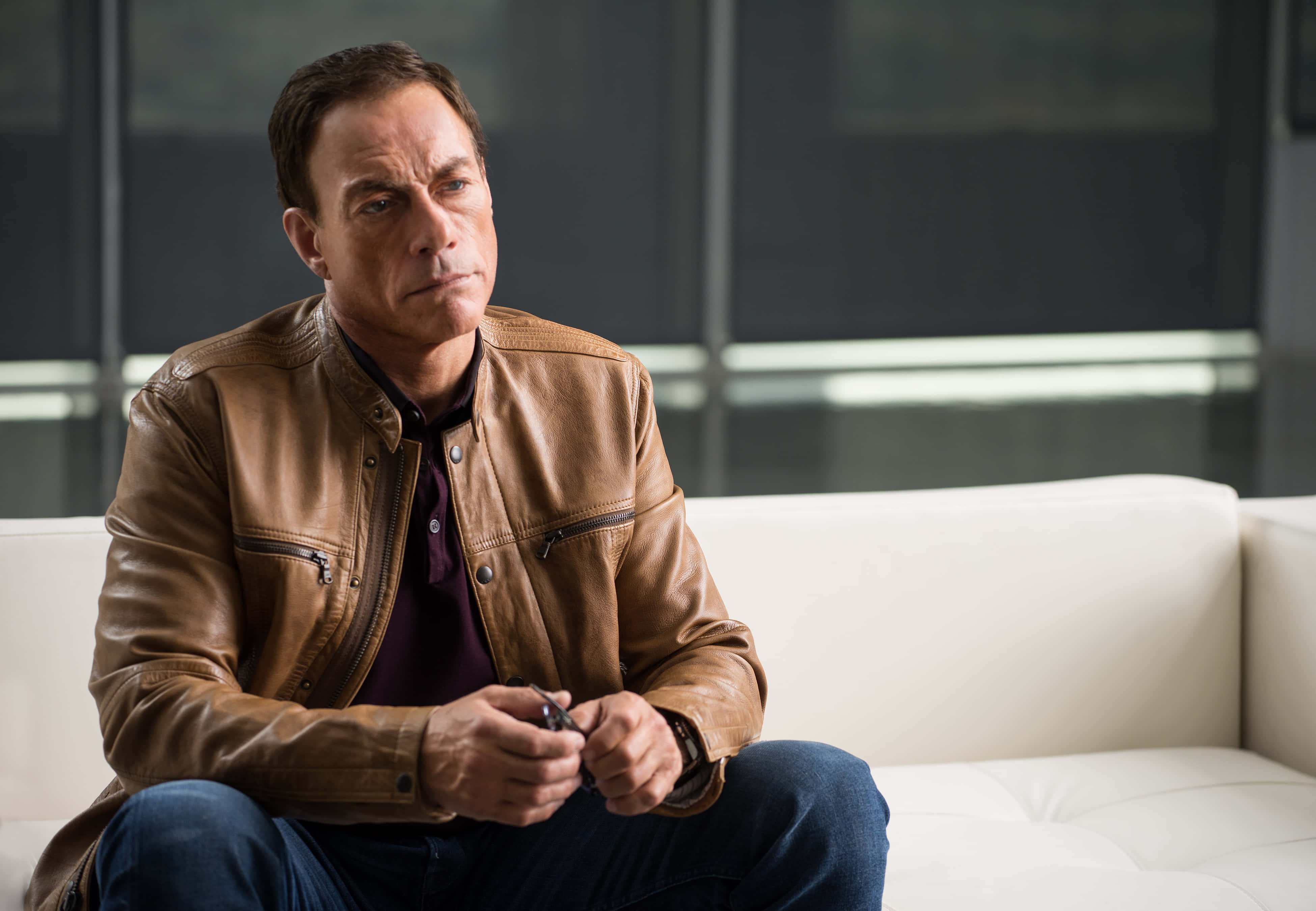 Jean Claude Van Damme, brown leather jacket, white couch, 4K Desktop Wallpaper