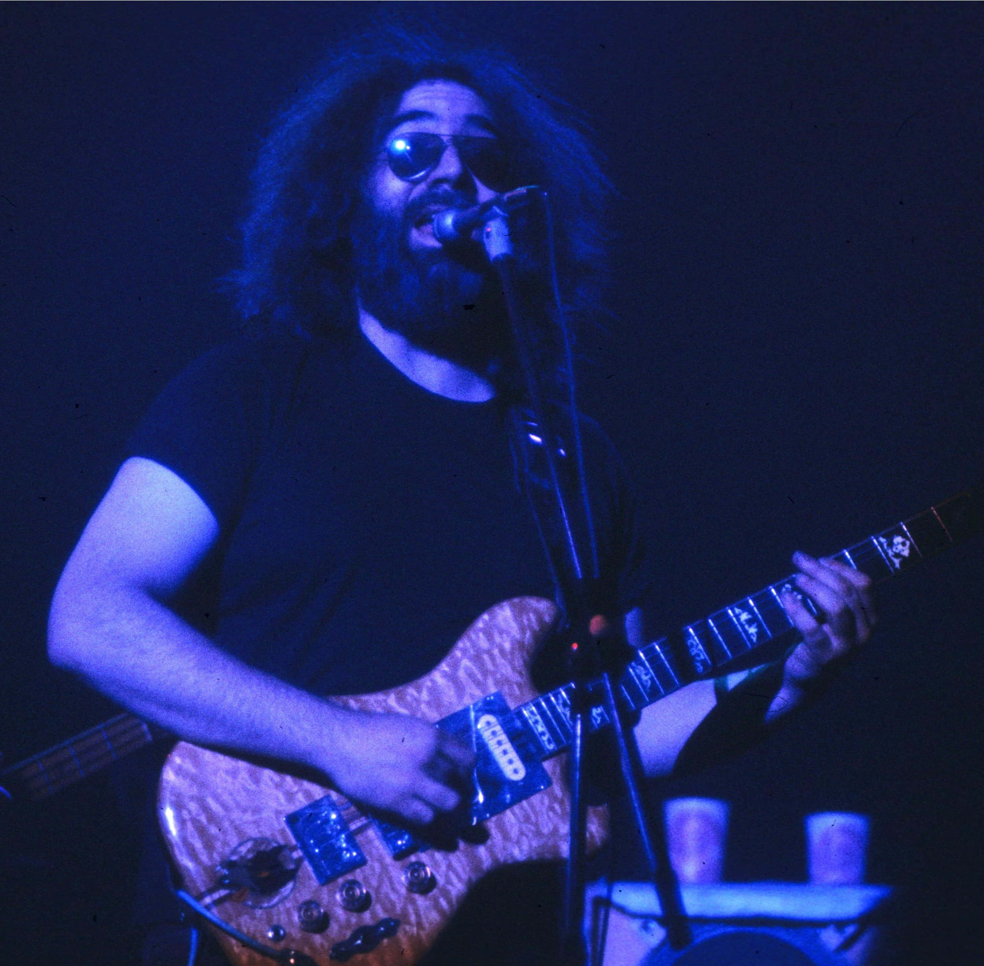 Jerry Garcia, wood grain electric guitar, blue stage lights, 2K Desktop Wallpaper