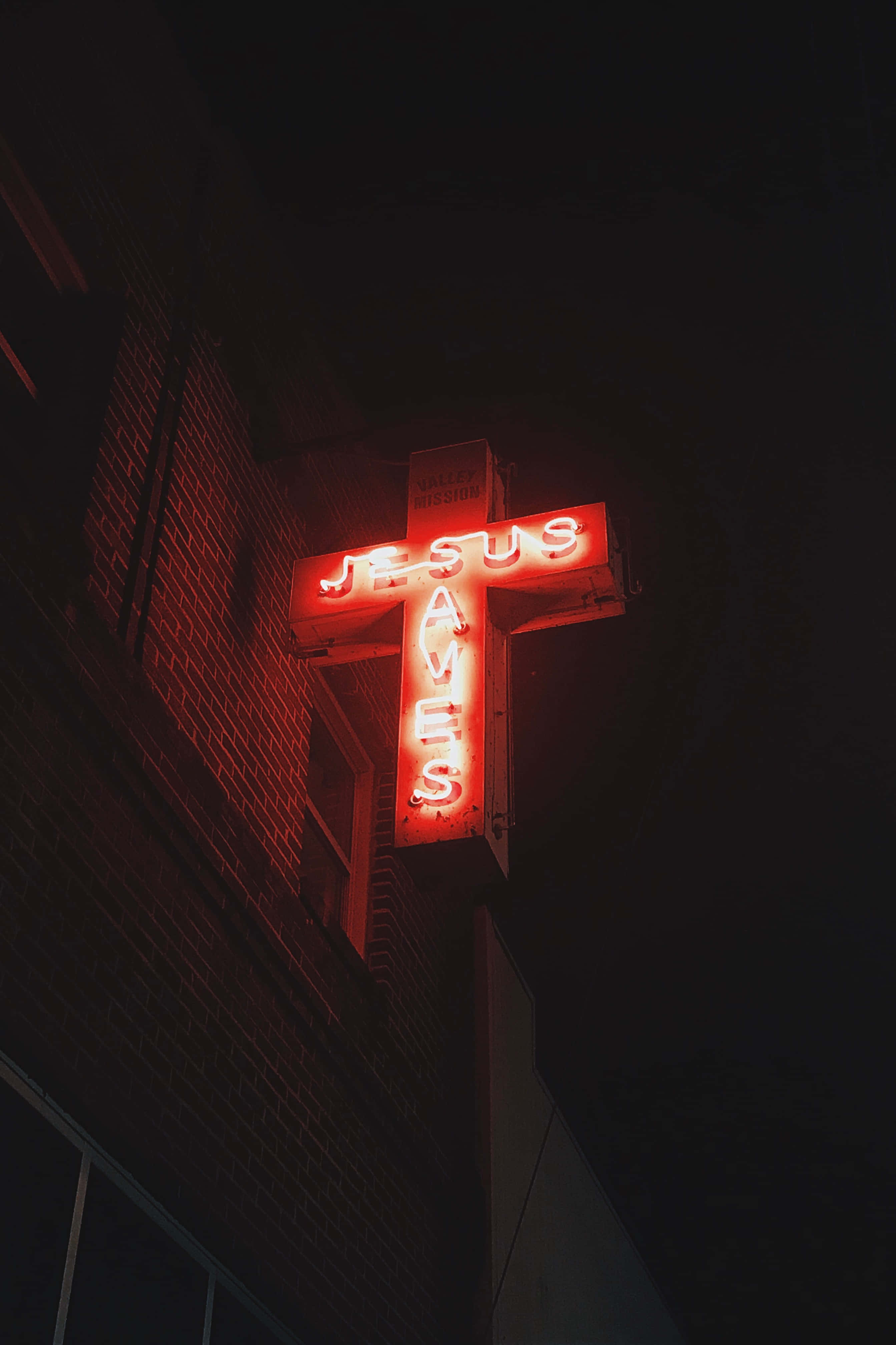 JESUS SAVES, glowing red neon cross sign, brick building, 4K Phone Wallpaper