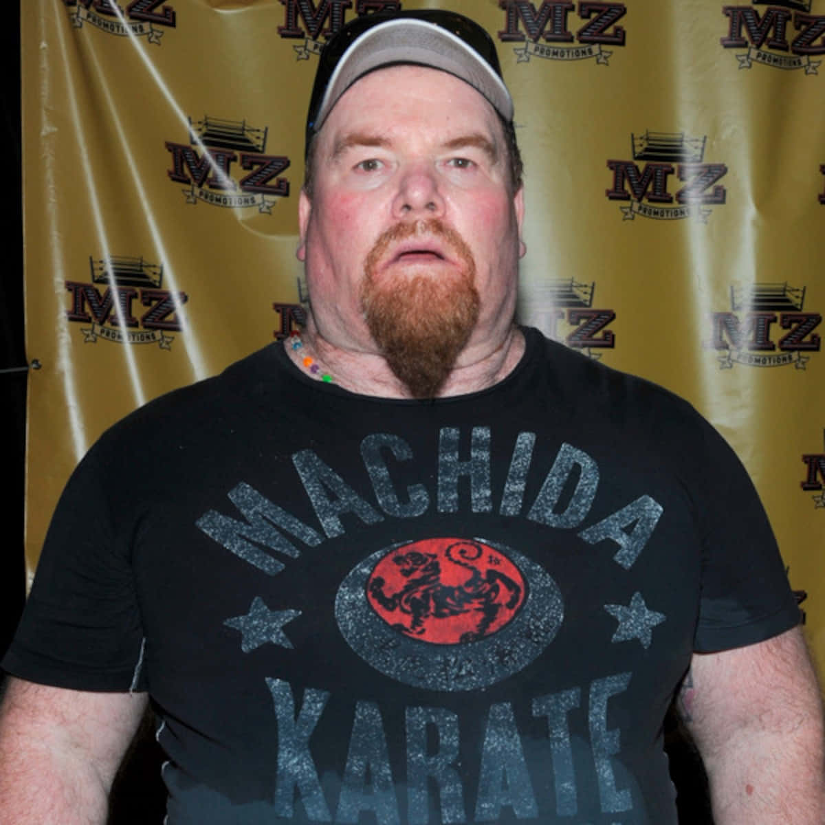 Jim Neidhart, black cap, gold MZ Promotions backdrop, SD Desktop Wallpaper
