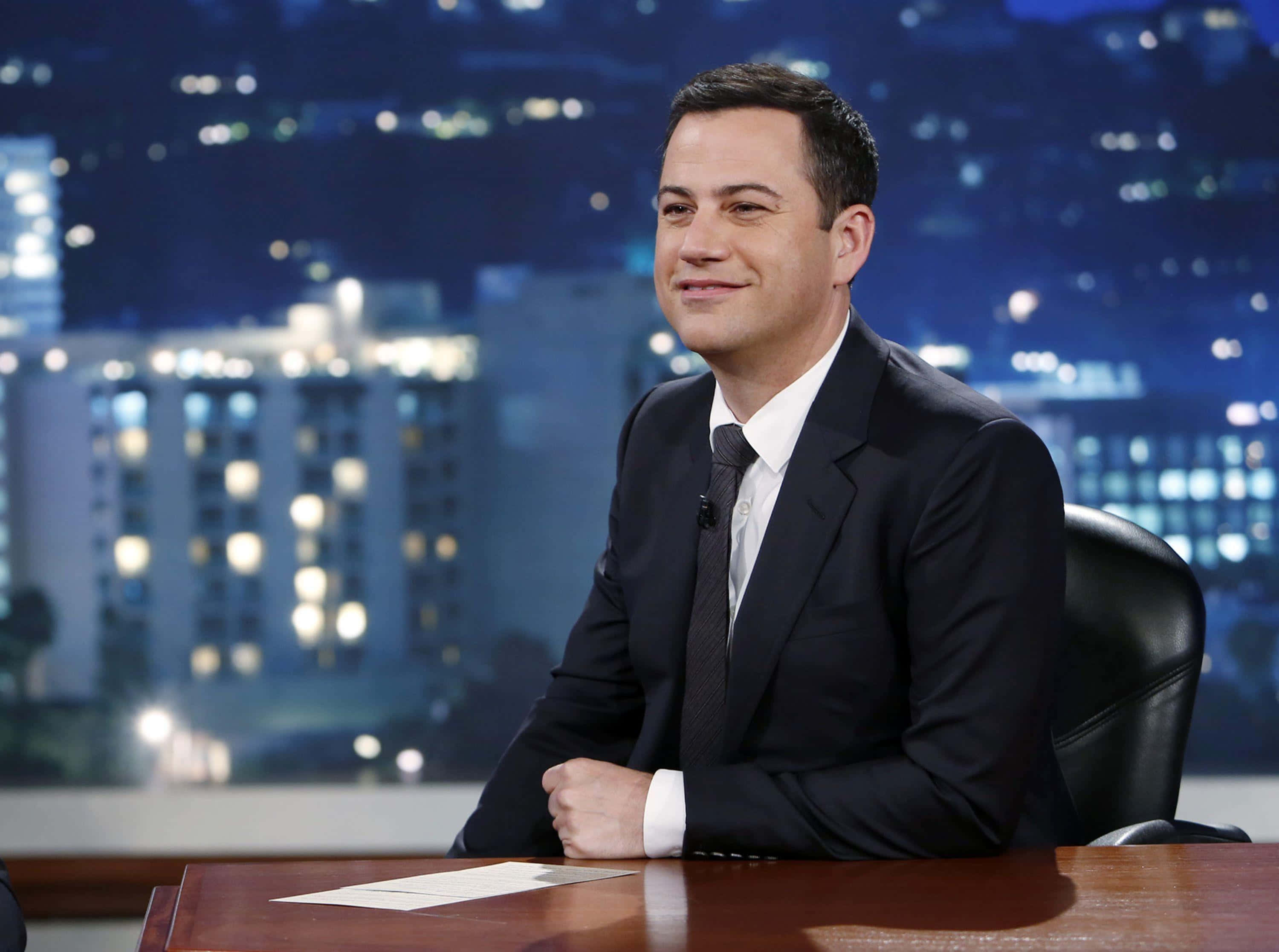 Jimmy Kimmel, dark suit, wooden desk, 2K Desktop Wallpaper