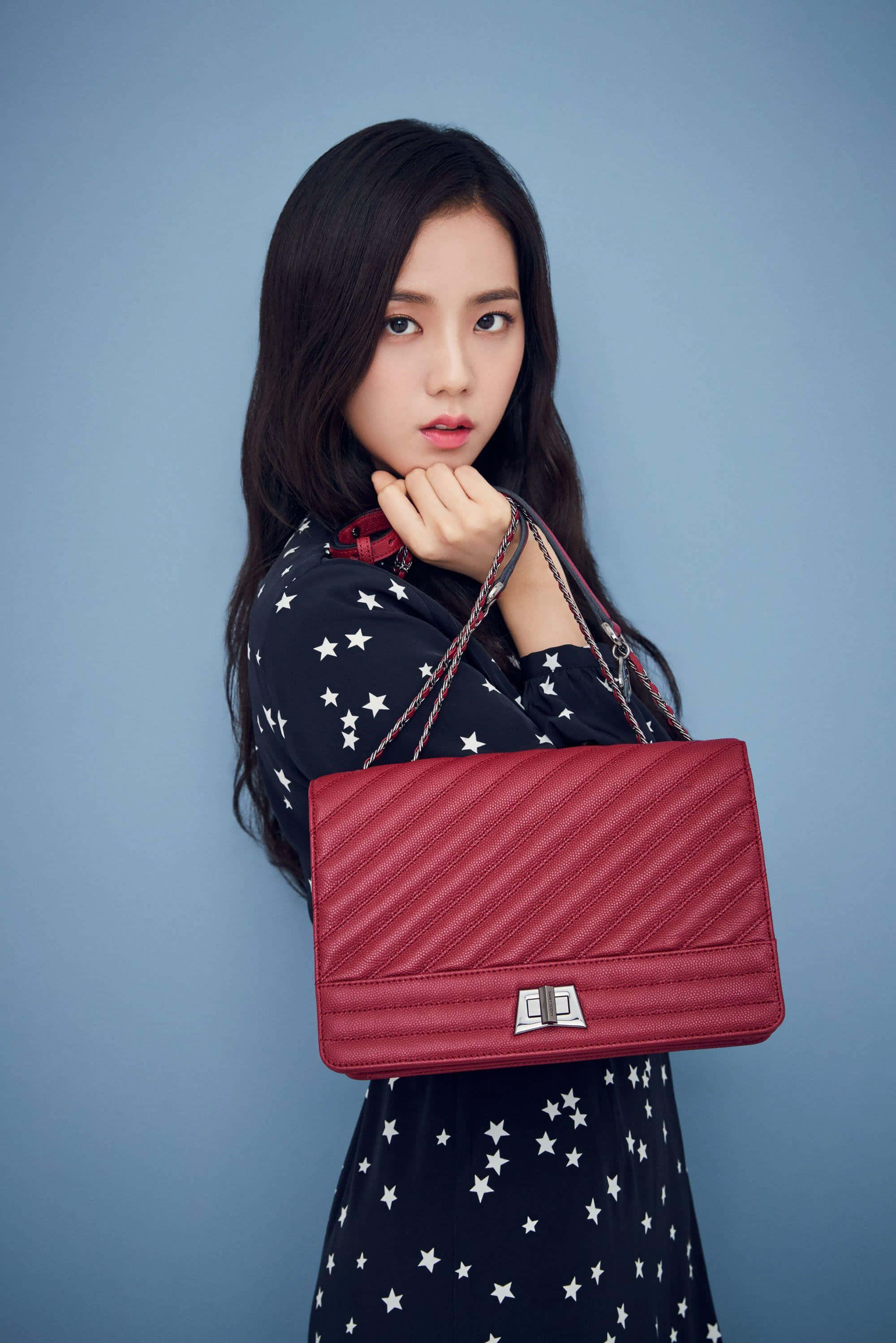 Jisoo Blackpink, red quilted handbag, solid blue studio background, 2K Phone Wallpaper