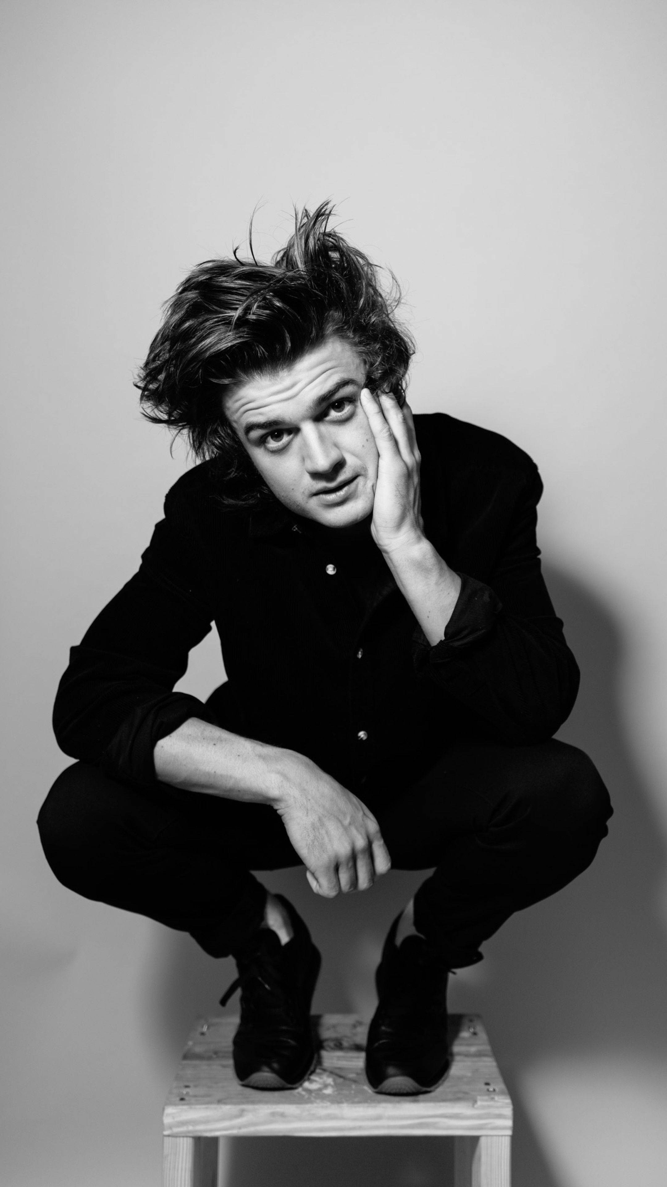 Joe Keery, tousled hair, wooden stool, 4K Phone Wallpaper