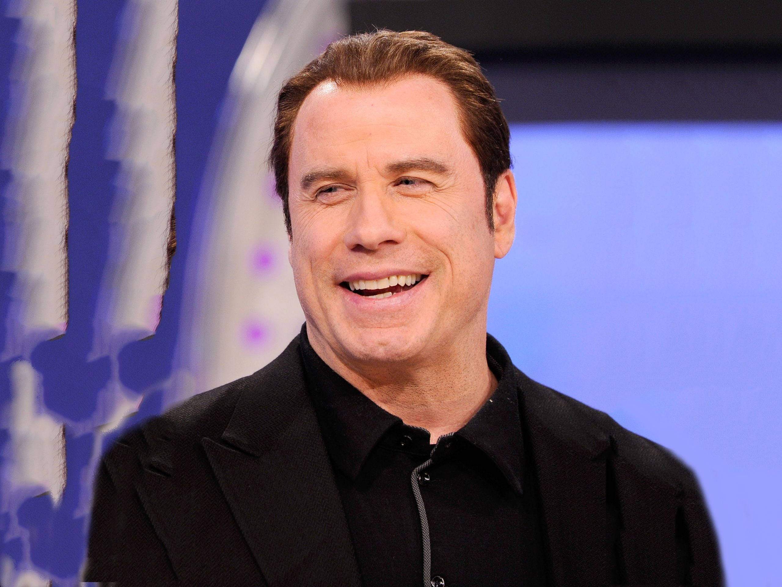 John Travolta, black suit, blurred blue and white studio backdrop, 2K Desktop Wallpaper