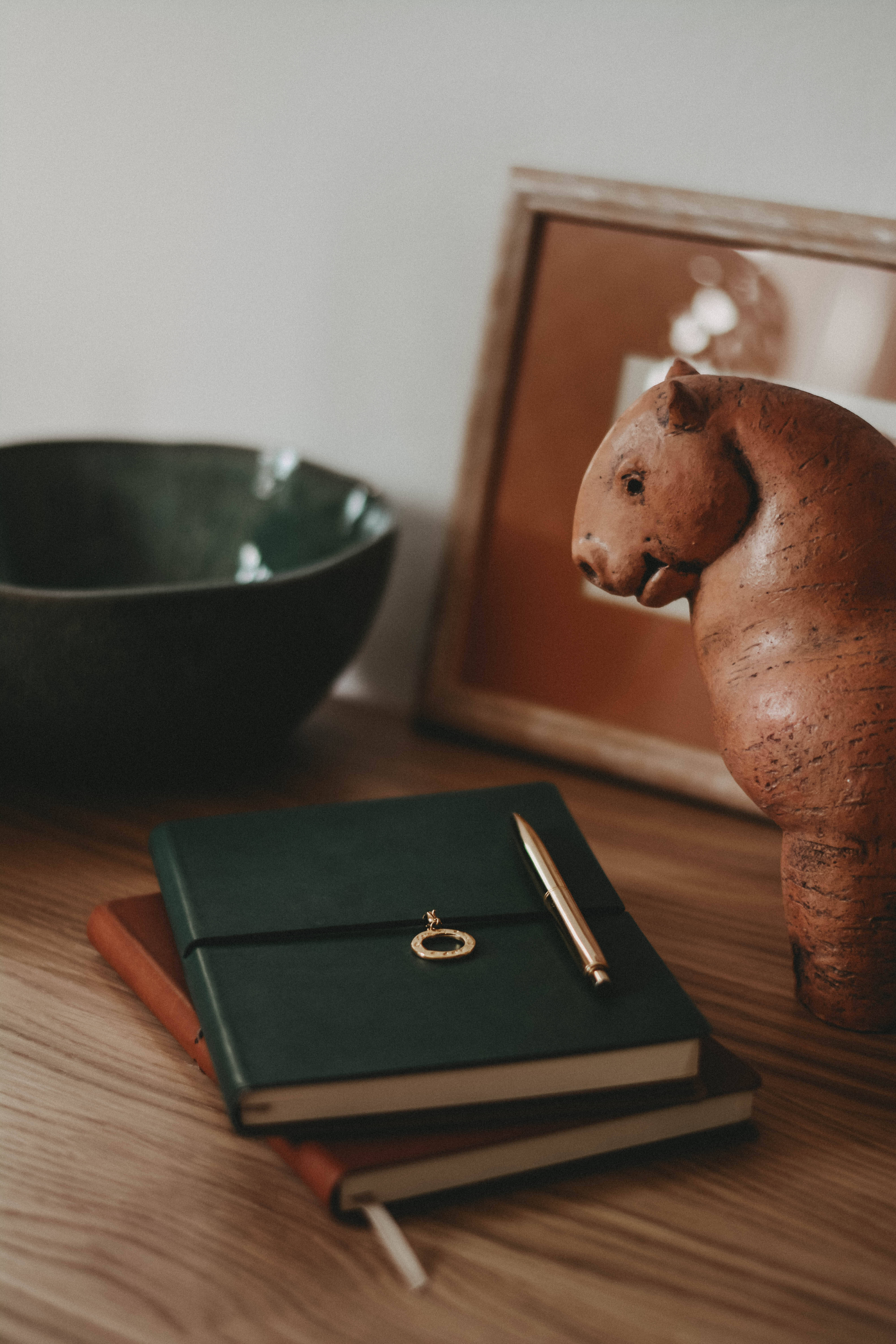 green notebook, gold pen, wooden wombat figurine, 5K Phone Wallpaper