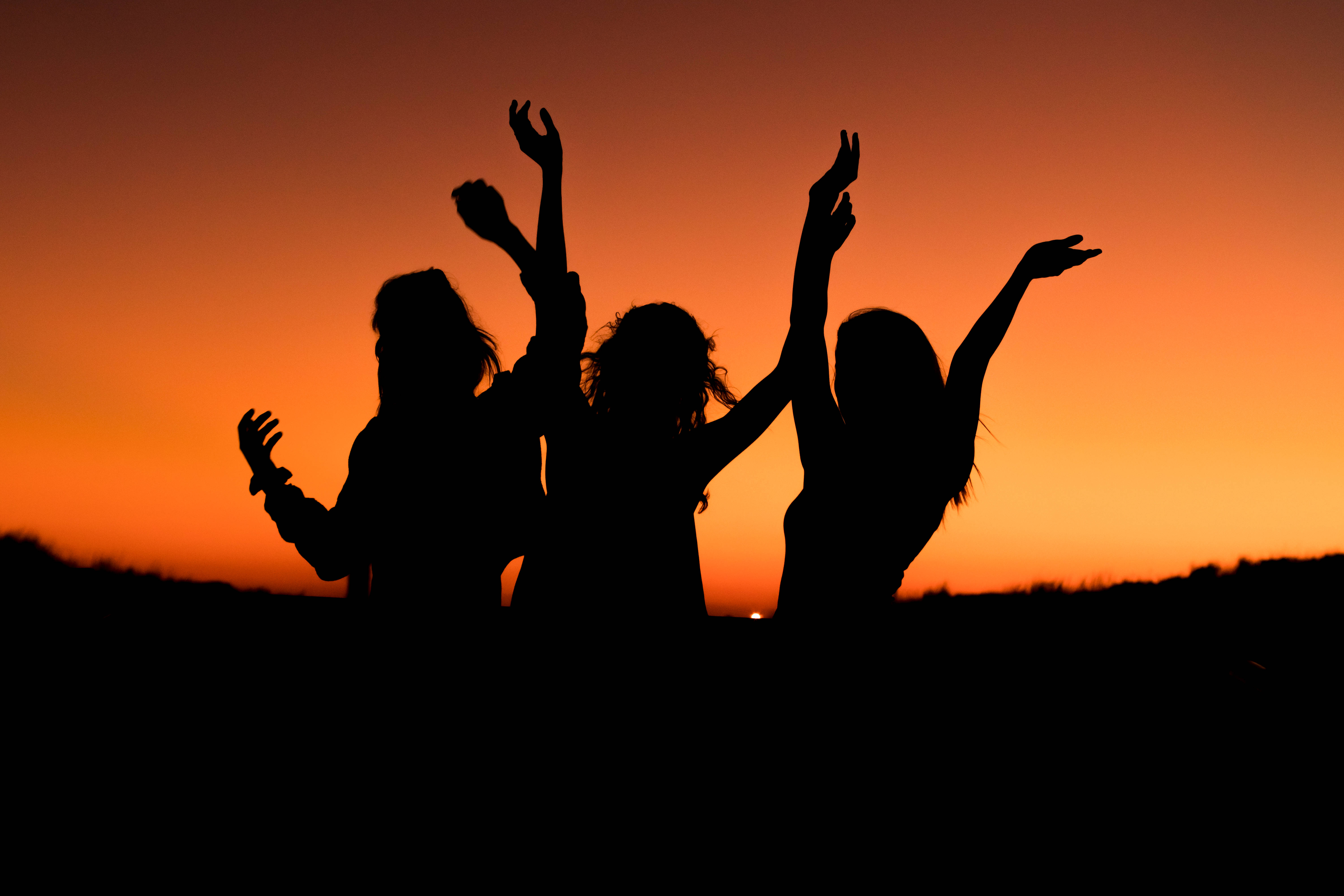 fiery orange sunset sky, three joyful silhouettes, celebration atmosphere, 5K Desktop Wallpaper