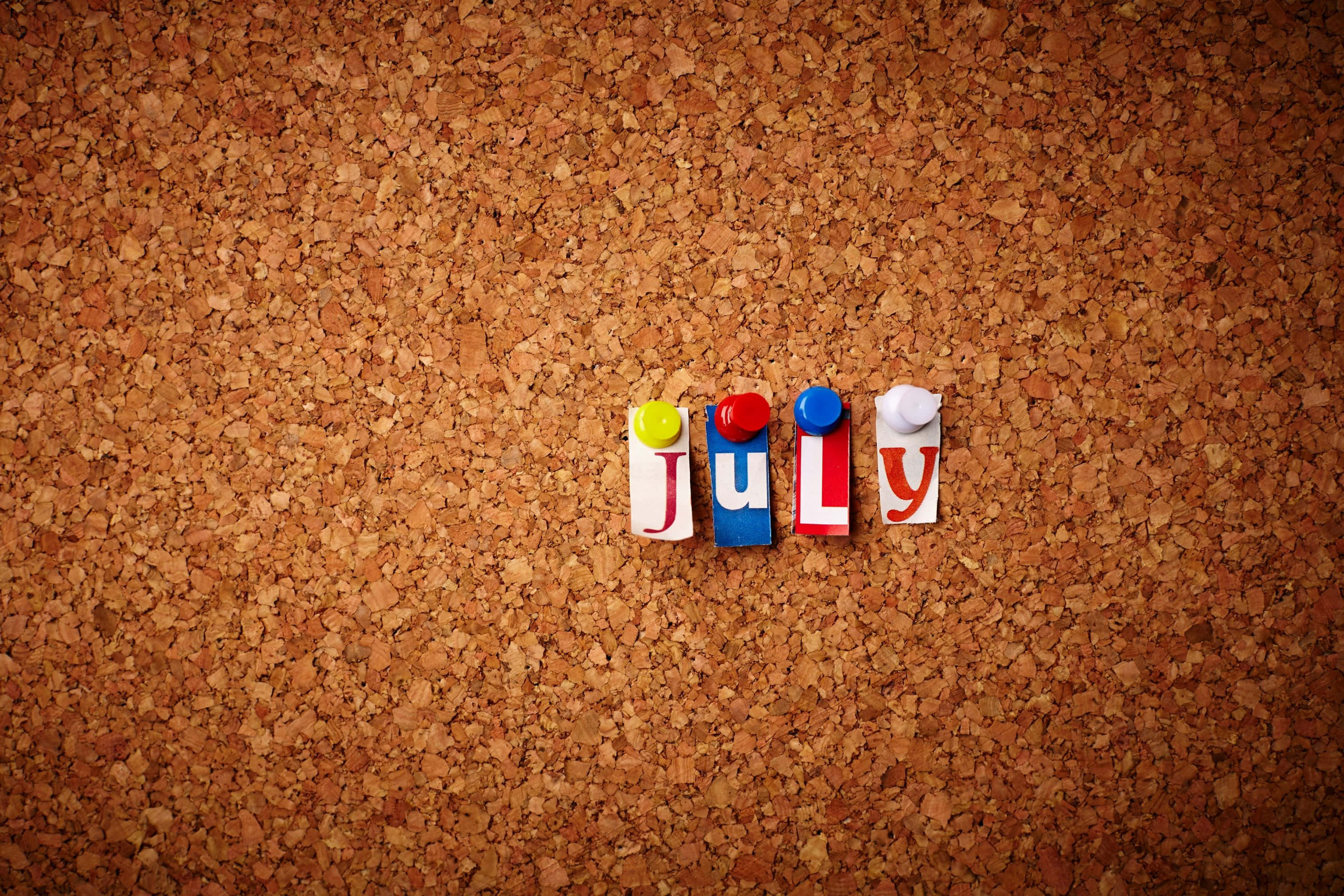 JULY, colorful letter blocks, textured brown corkboard surface, 2K Desktop Wallpaper