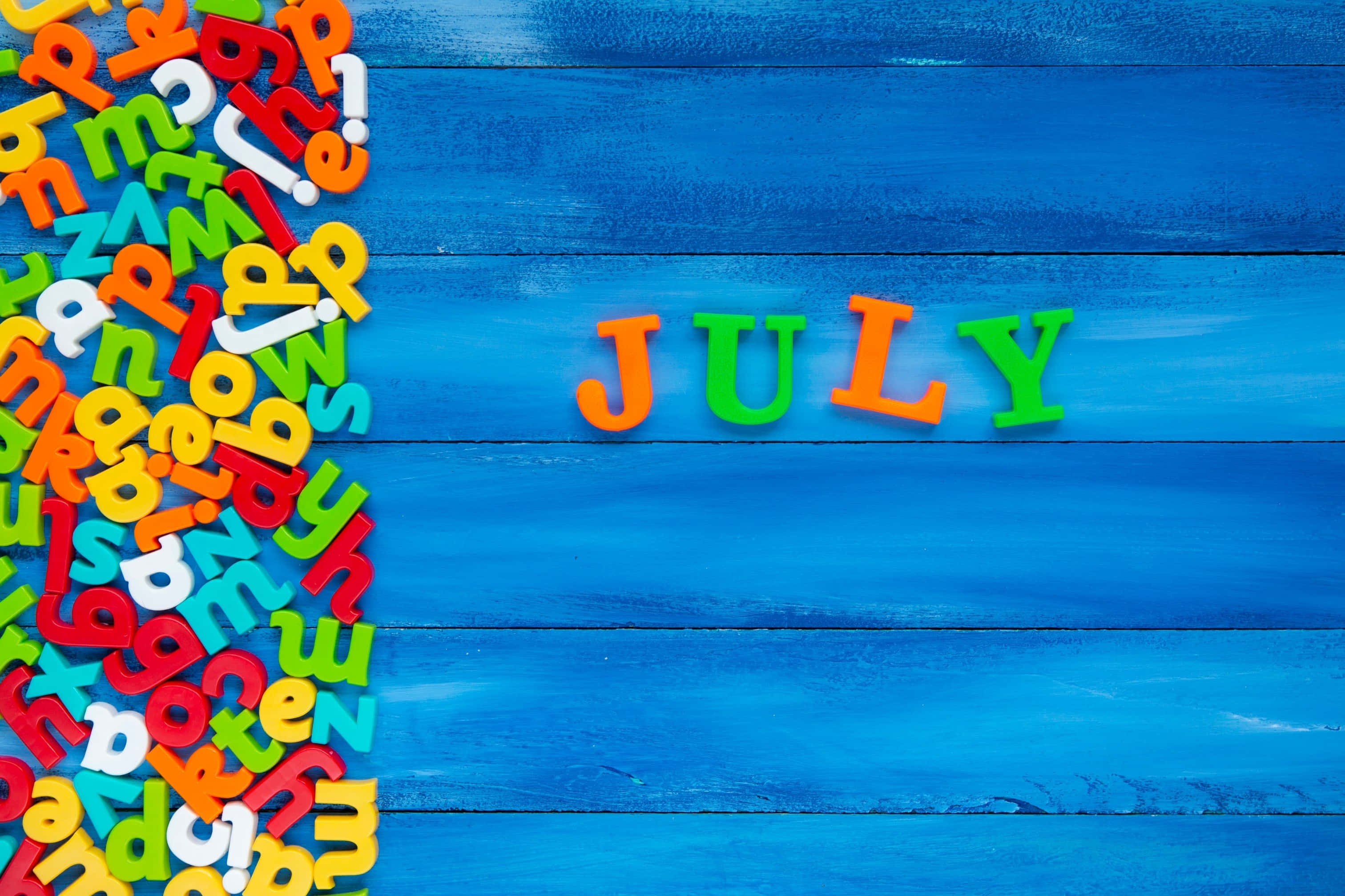 Colorful July Letterson, blue background, magnetic letters, 2K Desktop Wallpaper