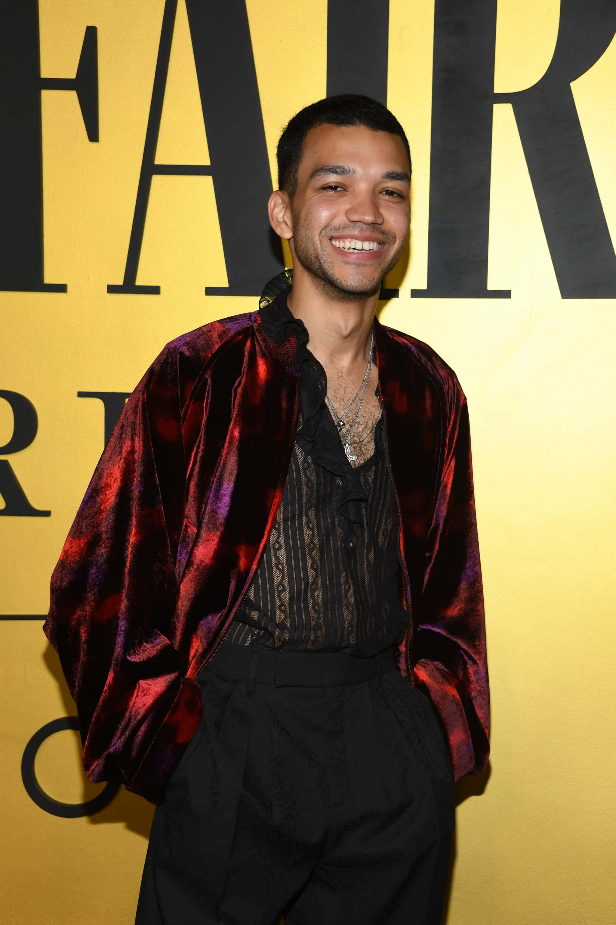 Justice Smith, red velvet jacket, bold yellow backdrop, 2K Phone Wallpaper